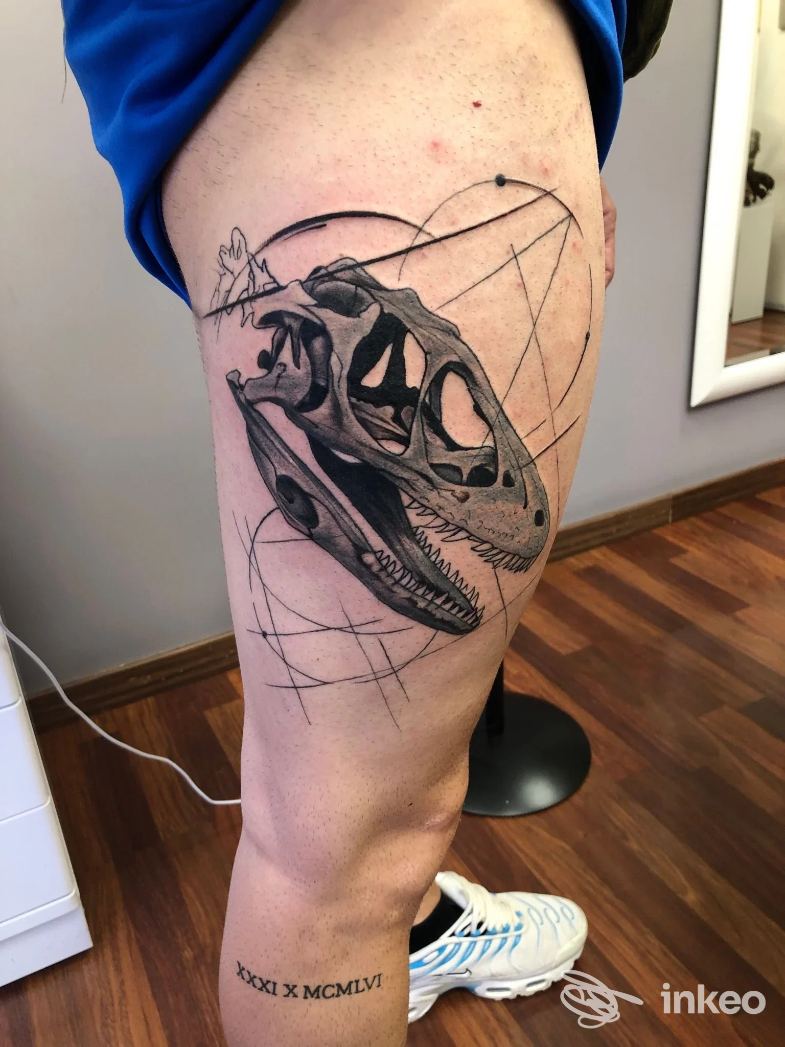 Tatuaggio su coscia con cranio di dinosauro in nero e grigio, linee geometriche; Filippo Tattoo Artist, San Donà di Piave.