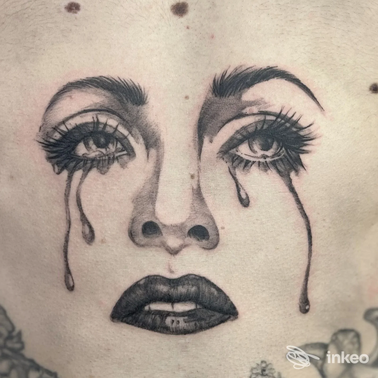 Grande tatuaggio in bianco e nero di un volto piangente sul petto, eseguito da Dragonfly Tattoo a Spinea.