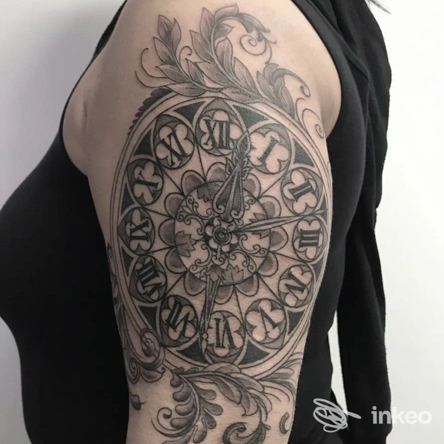 Grande tatuaggio blackwork circolare sul deltoide con numeri romani e decorazioni floreali, foto fornita da Dragonfly Tattoo, Spinea.
