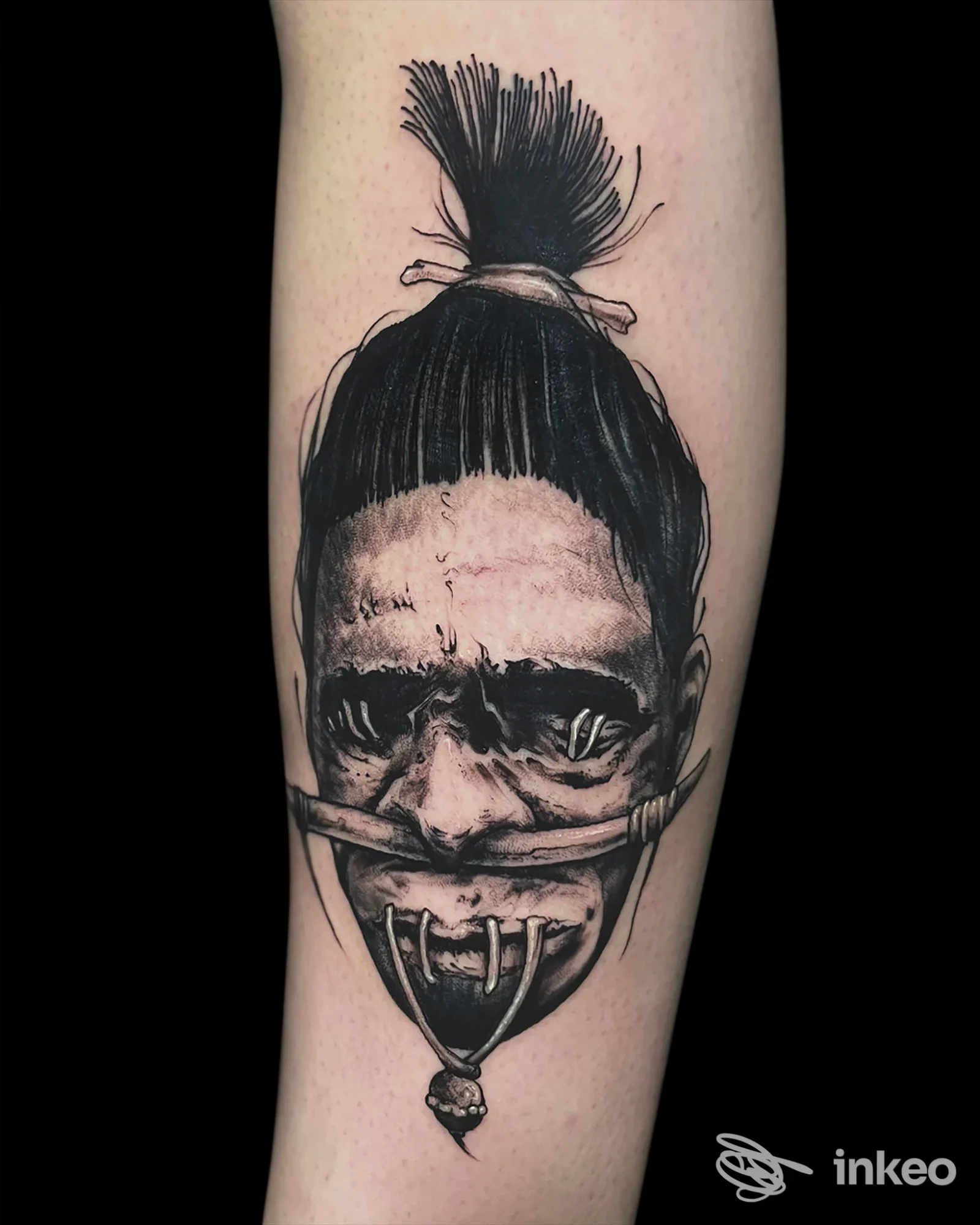 Tatuaggio in bianco e nero su avambraccio raffigurante un volto stilizzato. Gravè de noir Tattoo Studio, Padova.