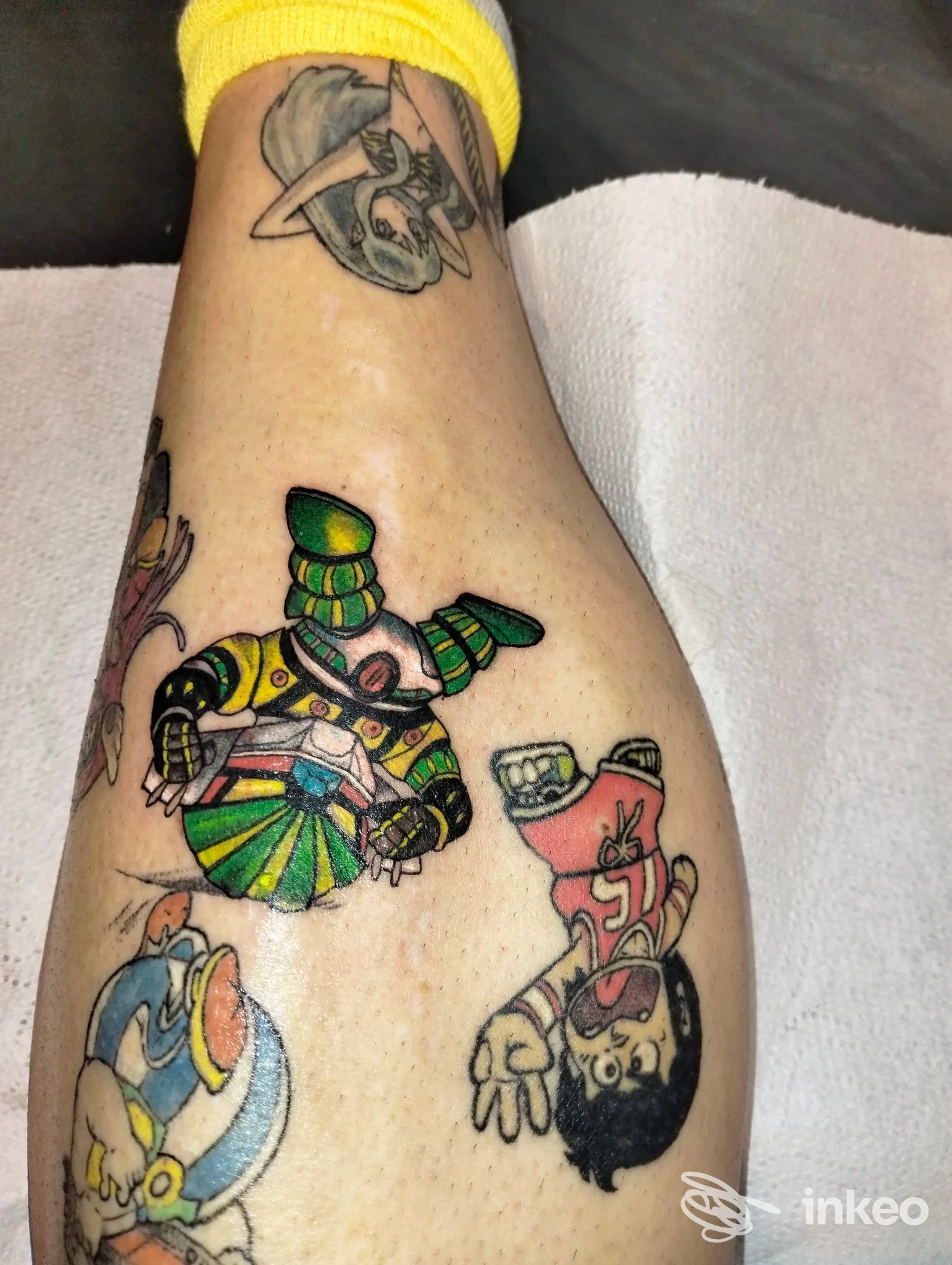 Polpaccio tatuato con vari soggetti in stile cartoon, colori vivaci e linee nette. ImmaginArti Tattoo, Isola Vicentina.