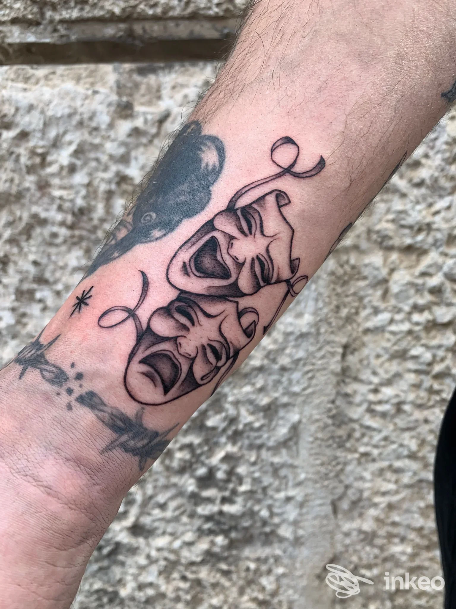 Tatuaggio di due maschere teatrali in bianco e nero sull'avambraccio, foto fornita da Hold Fast Tattoo, Verona.