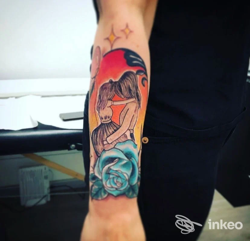 Tatuaggio colorato sull'avambraccio con due figure che si abbracciano sopra una rosa, GELA In-k TATTOO STUDIO Verona