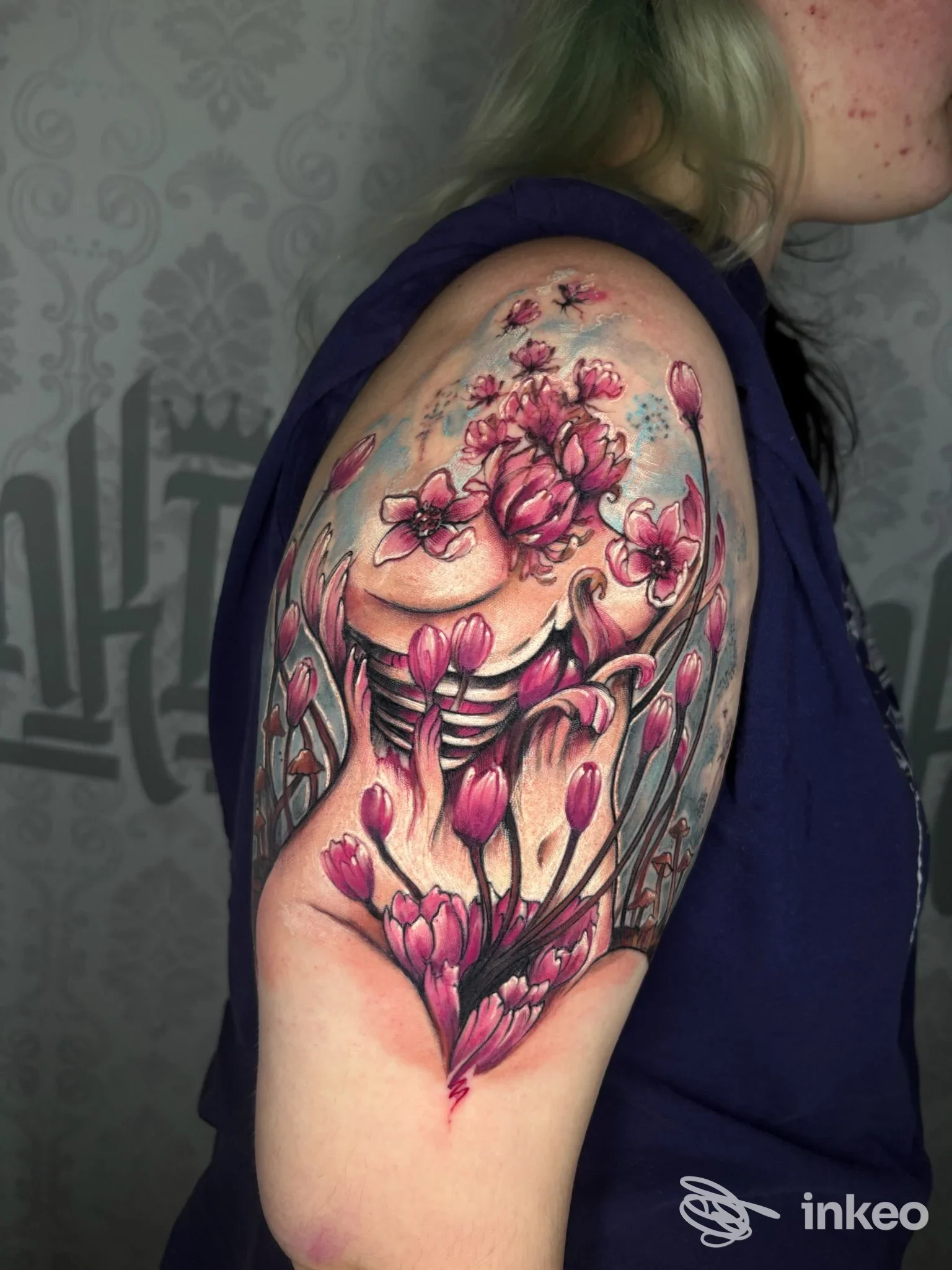 Tatuaggio colorato a fiori sulla spalla realizzato da InKing Tattoo a Caldogno, vista laterale del braccio.