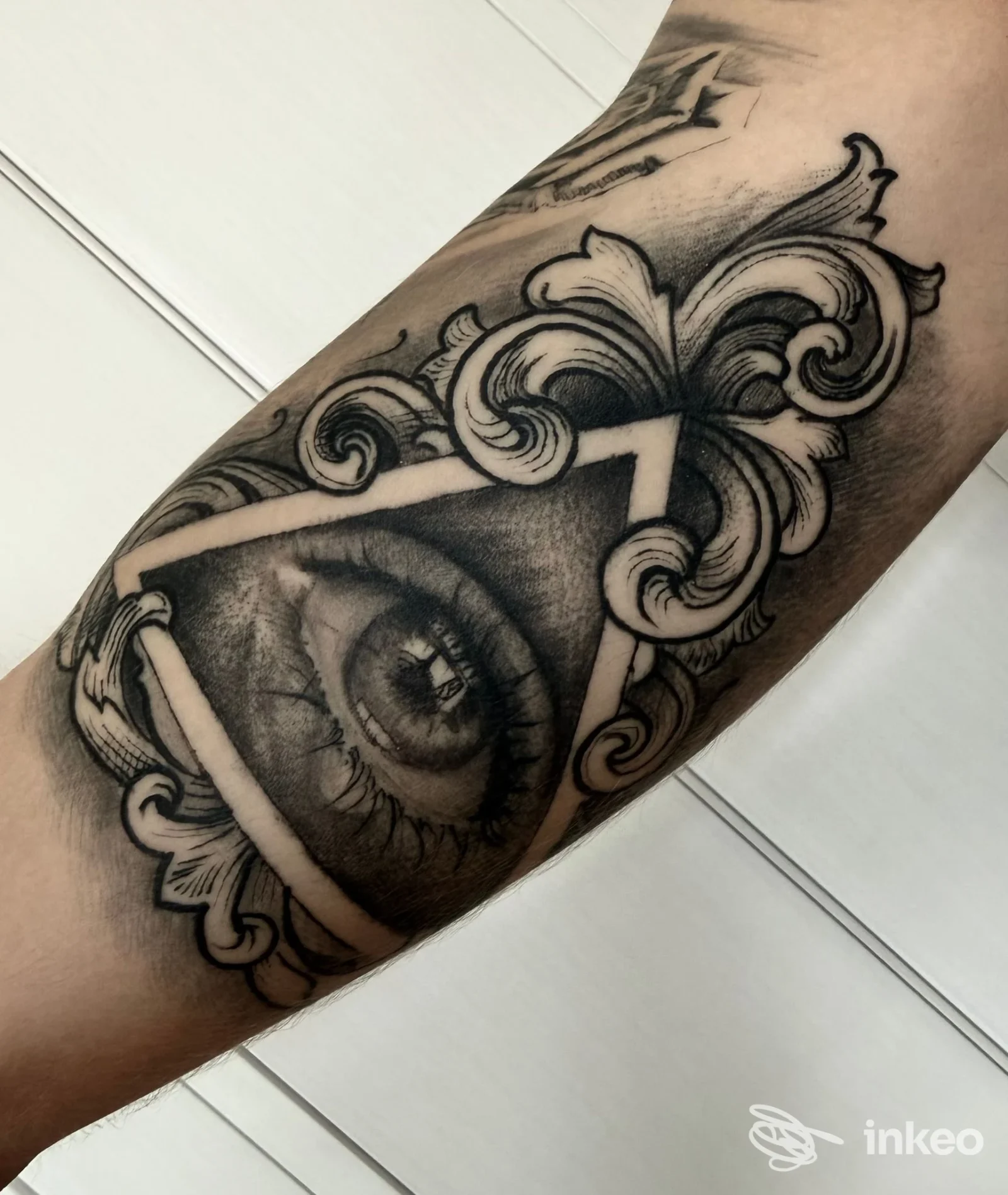 Tatuaggio realistico di un occhio in cornice ornamentale sull'avambraccio, InKing Tattoo, Caldogno.