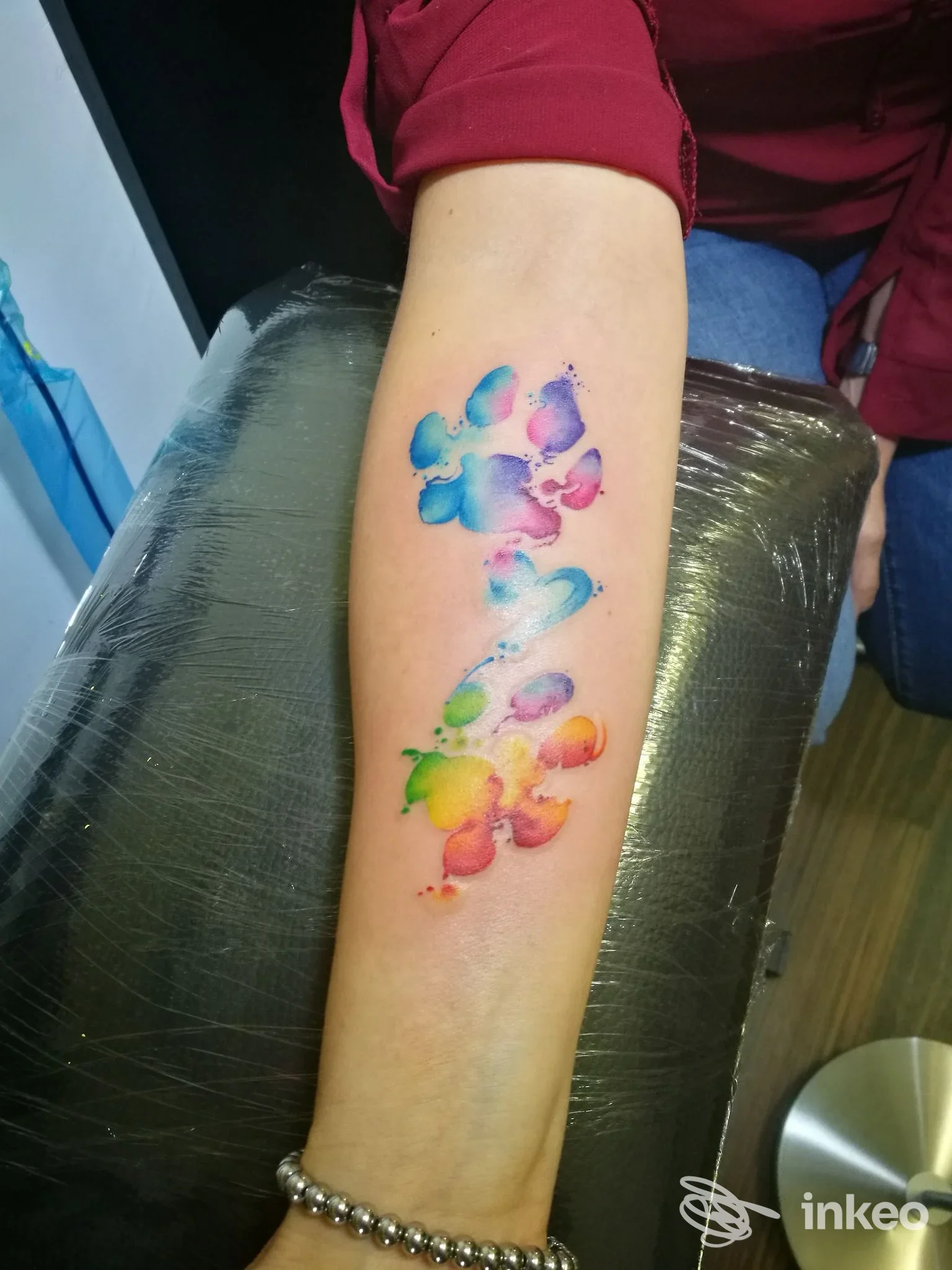 Braccio adulto con tatuaggio colorato in stile acquerello di farfalle multicolori lungo l’avambraccio, eseguito su pelle nuda.
