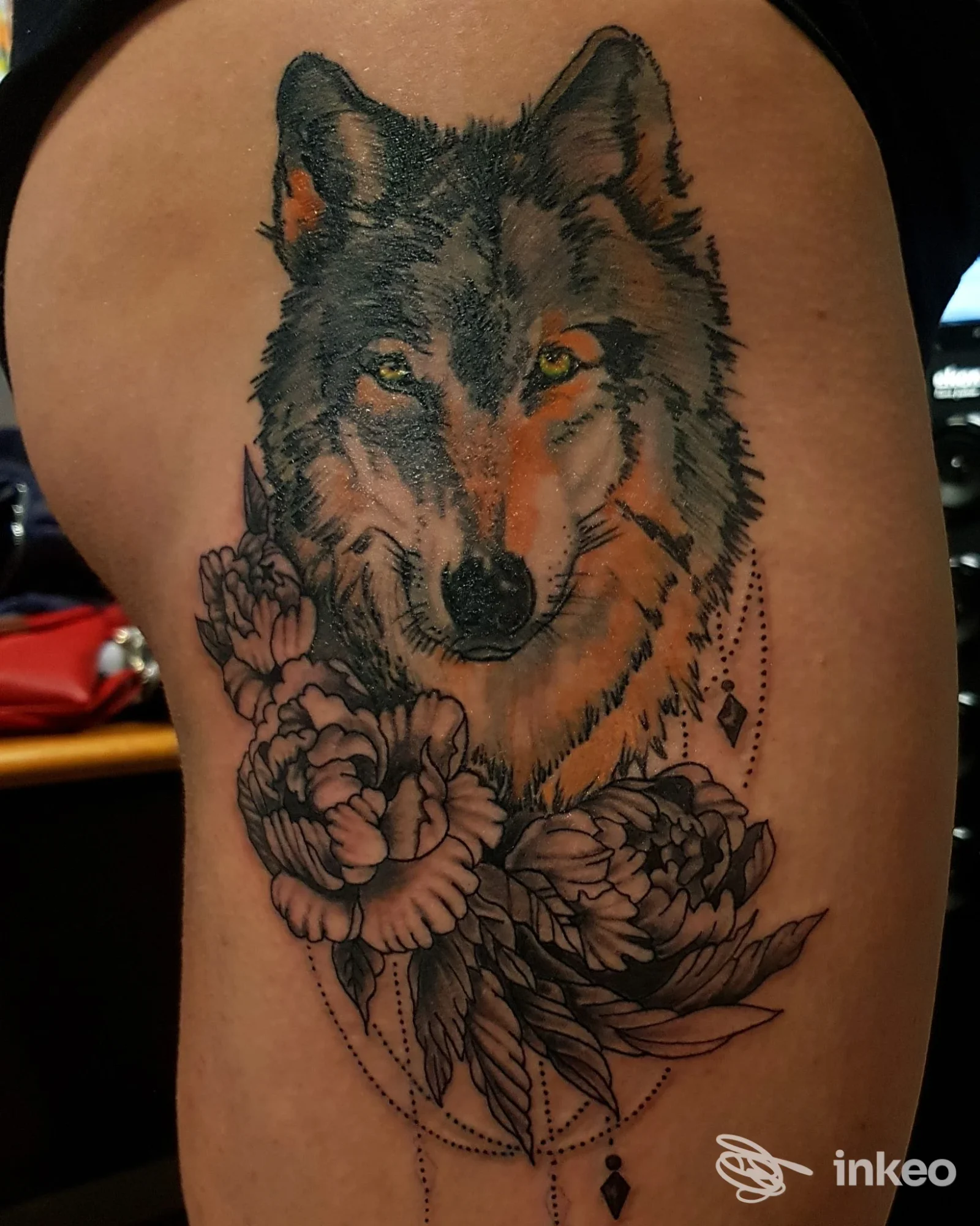 Grande tatuaggio di lupo realistico con fiori sul fianco/coscia, realizzato da Ink Society Tattoo a Grisignano di Zocco.