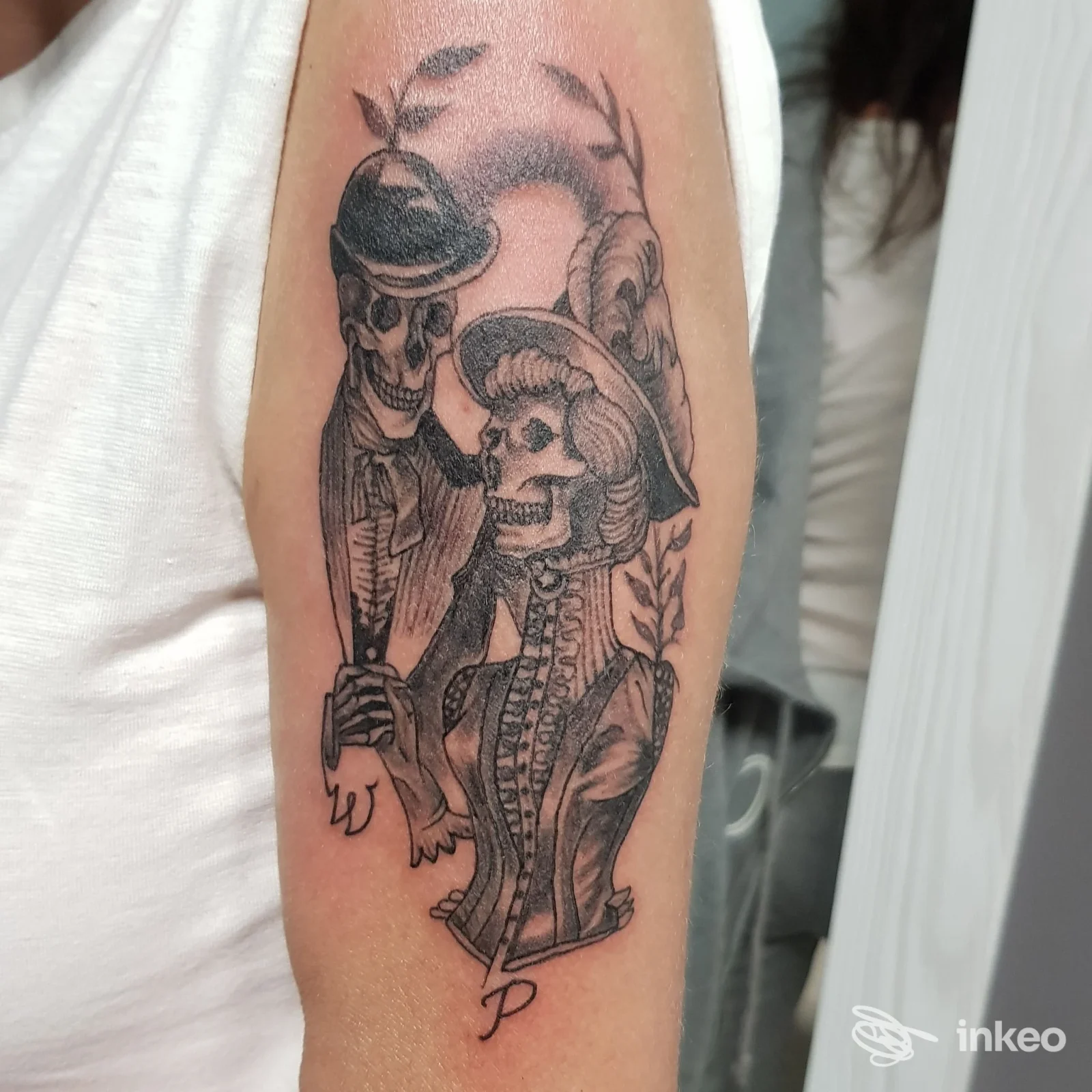 Tatuaggio black and grey di teschi in abiti vittoriani sull'avambraccio interno, fotografato nello studio Ink Society Tattoo a Grisignano di Zocco.