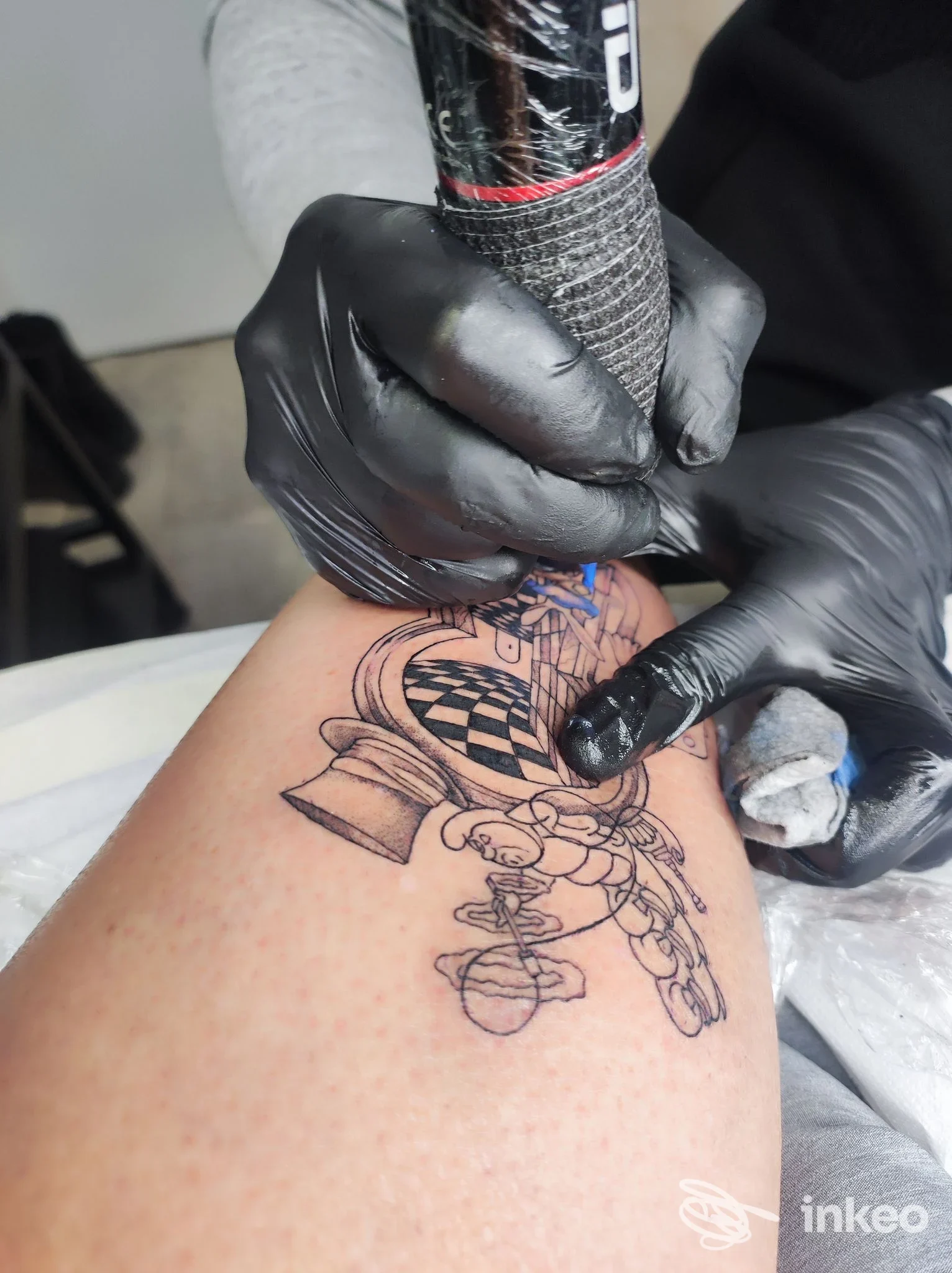 Tatuaggio linework in corso sull'avambraccio, operatore con guanti neri e macchinetta. KATRAME Tattoo Studio, Schio.