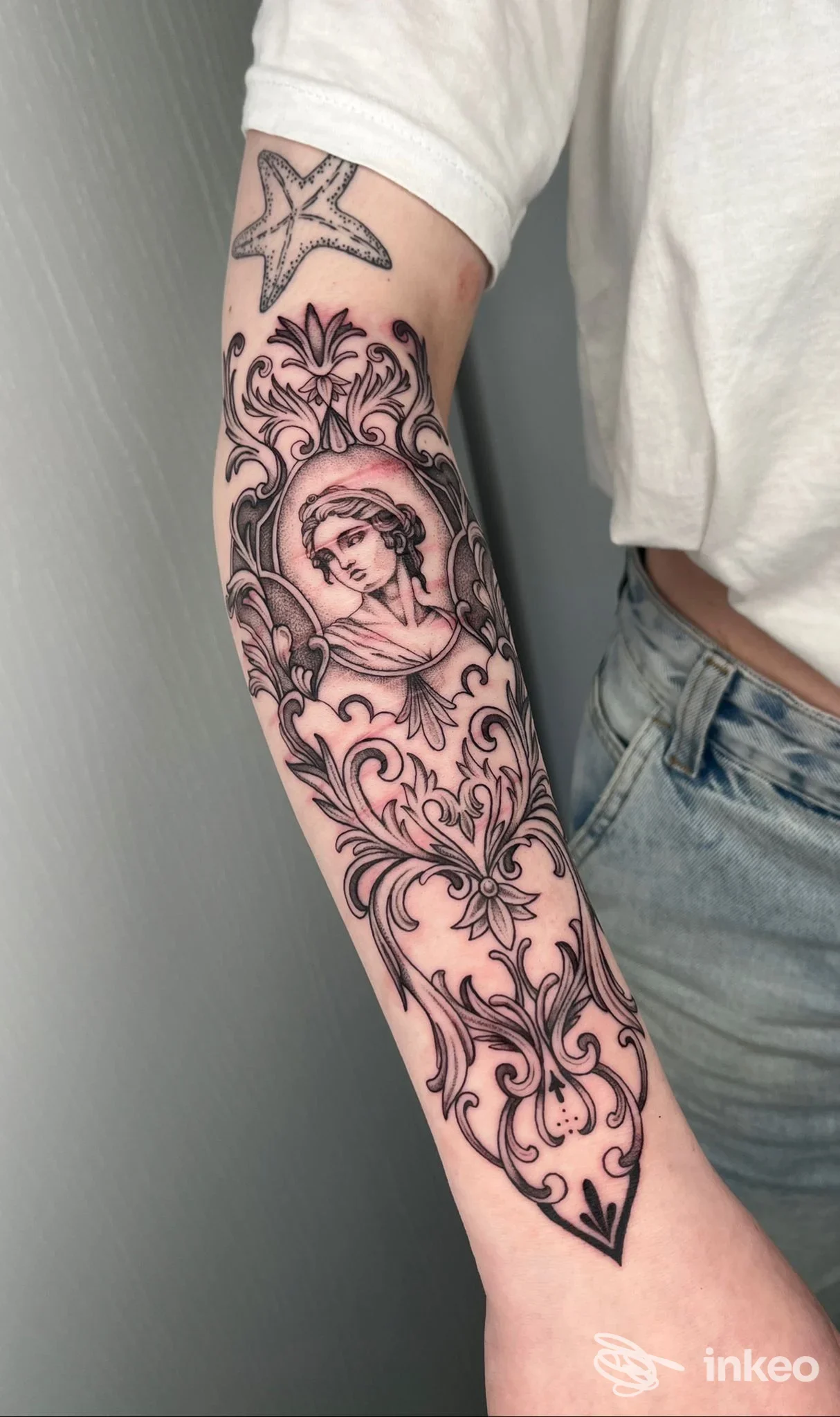 Tatuaggio in bianco e nero ornamentale con ritratto sull'avambraccio, foto fornita da KATRAME Tattoo Studio, Schio.
