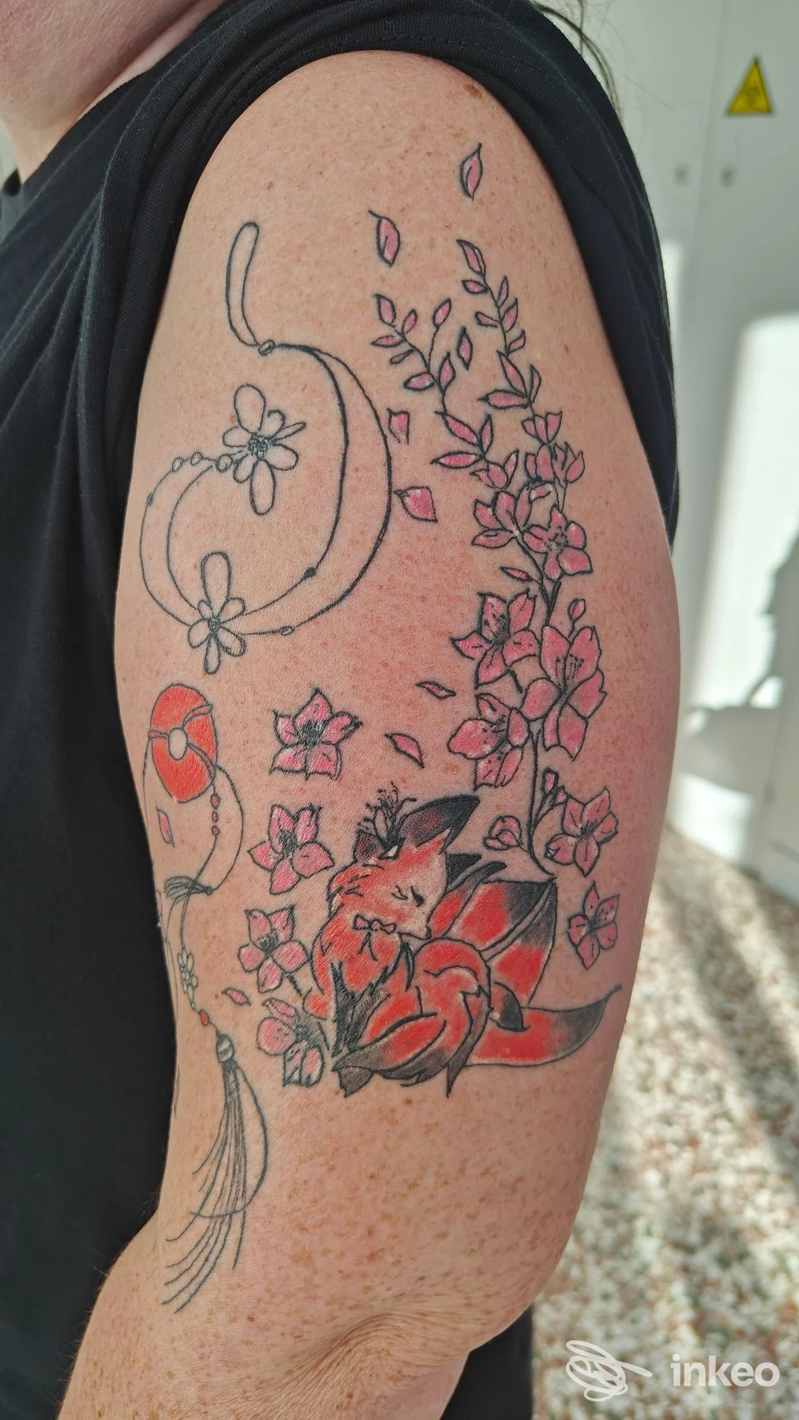 Tatuaggio a colori sul braccio superiore con una volpe e fiori su pelle reale — Jolie Tattoo Piercing di Luca Marinello, Castelfranco Veneto.