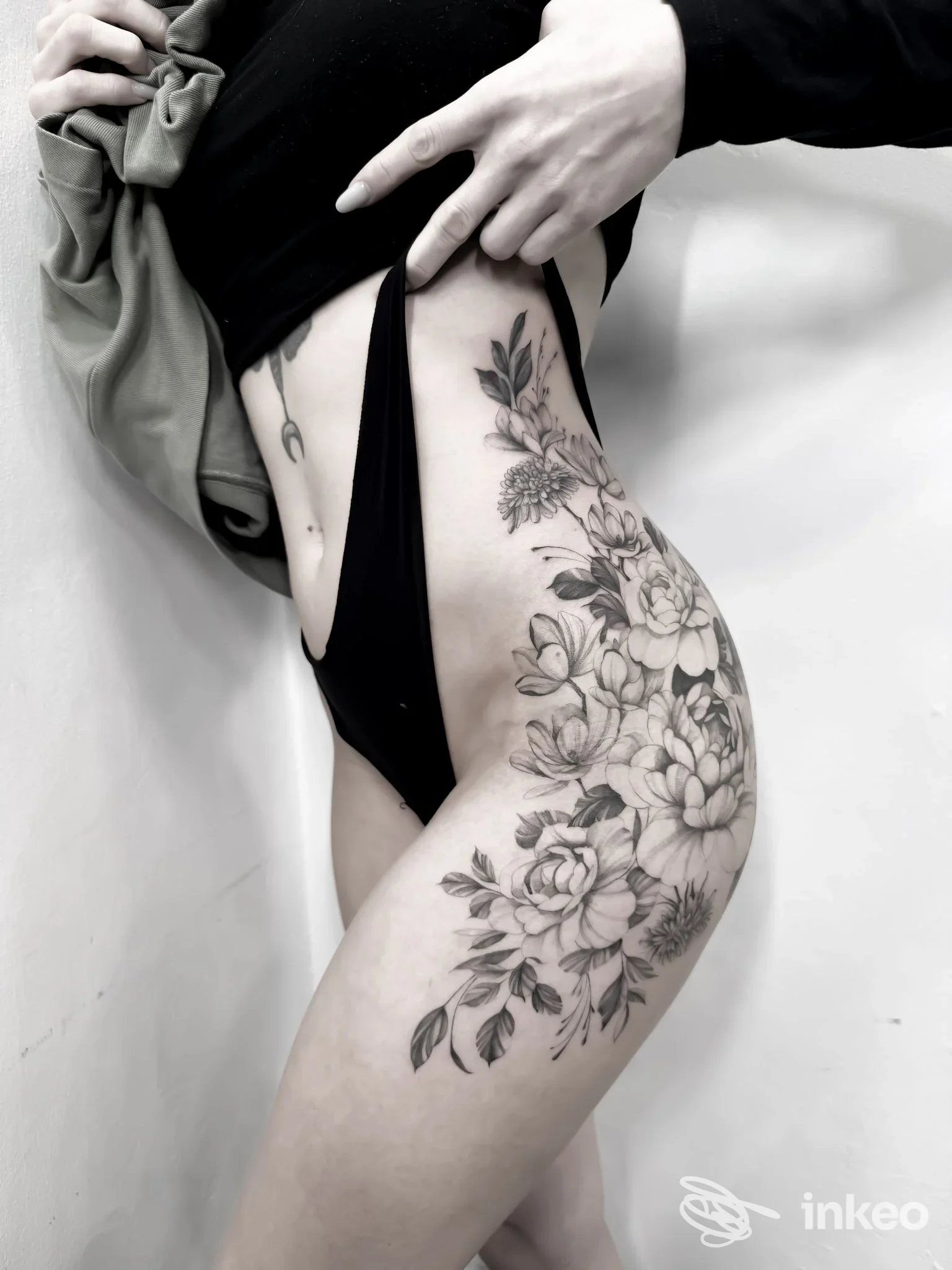 Ampia composizione floreale tatuata su fianco e coscia, foto per LABORATORIO TATTOO a Treviso.
