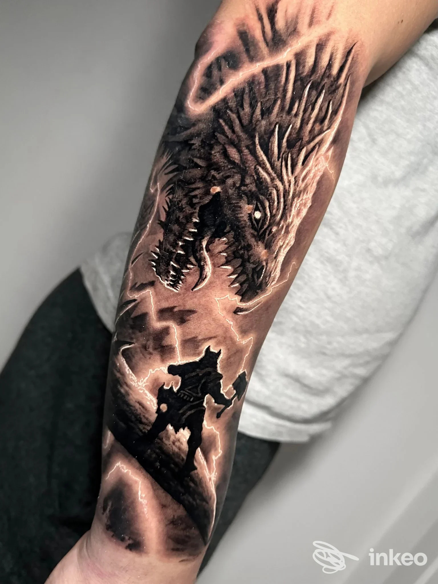 Tatuaggio realistico su avambraccio con testa di lupo e figura in silhouette, immagine fornita da Little Tattoo Verona, Verona.