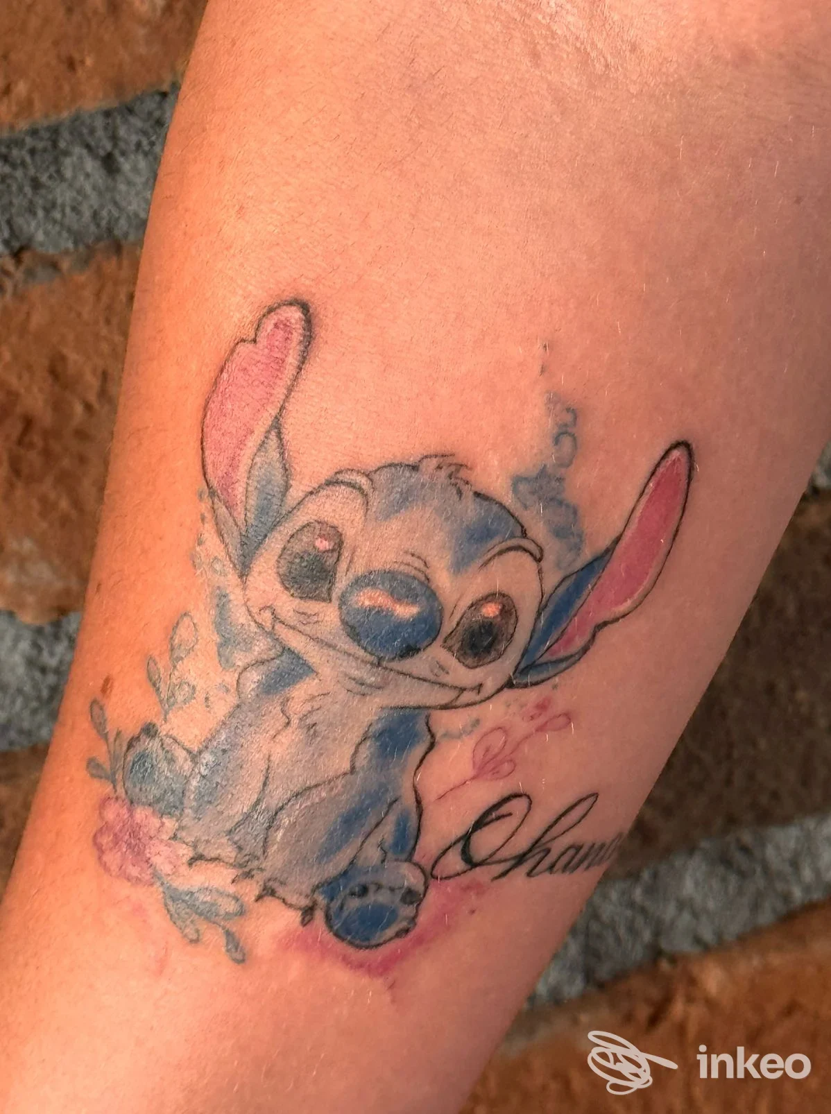 Tatuaggio colorato del personaggio Stitch con la scritta "Ohana" sull'avambraccio, foto fornita da Mara Tattoo Noventa di Piave.