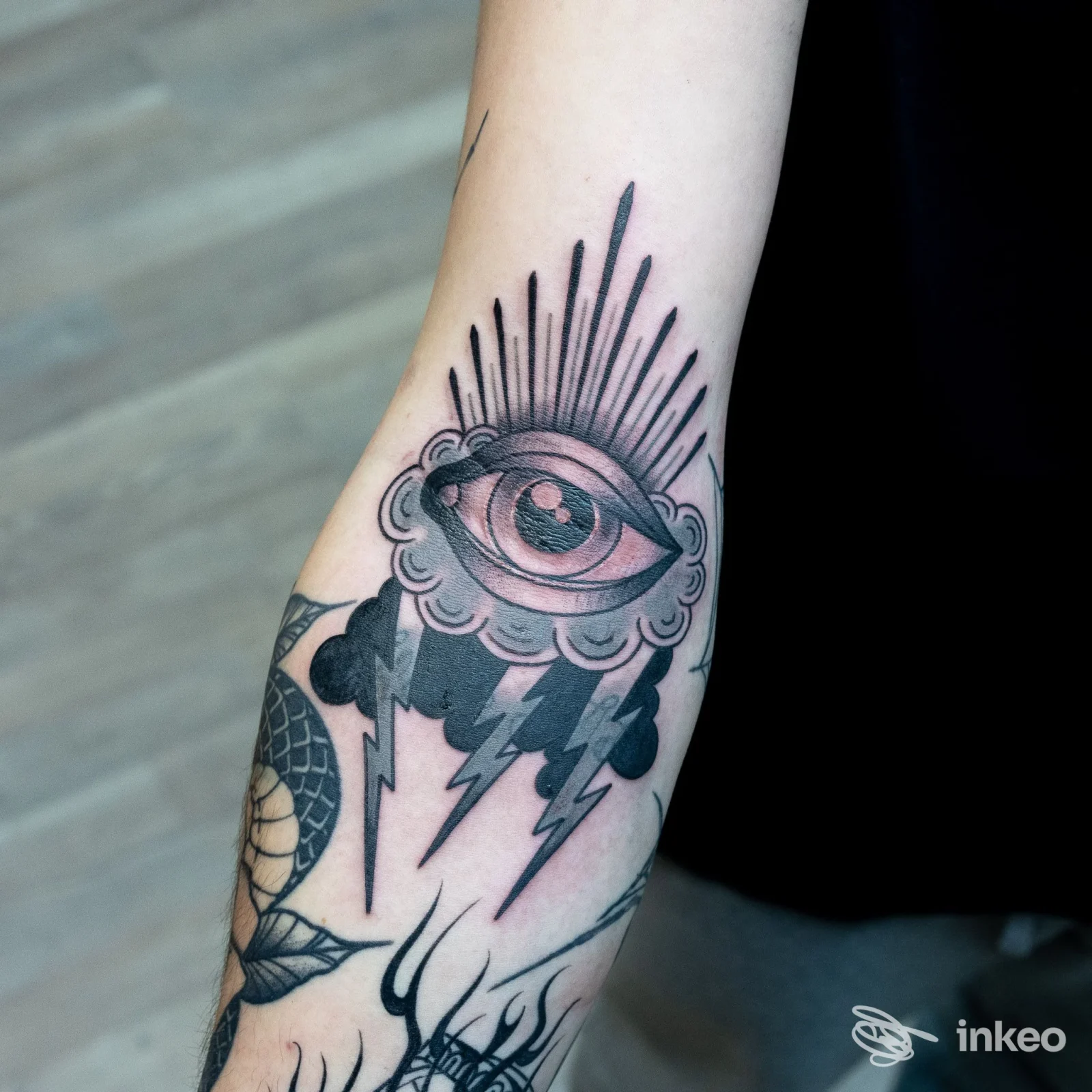 Tatuaggio occhio stilizzato con nuvola e fulmini sull'avambraccio, foto di NOTconventionalTATTOO a Vittorio Veneto.