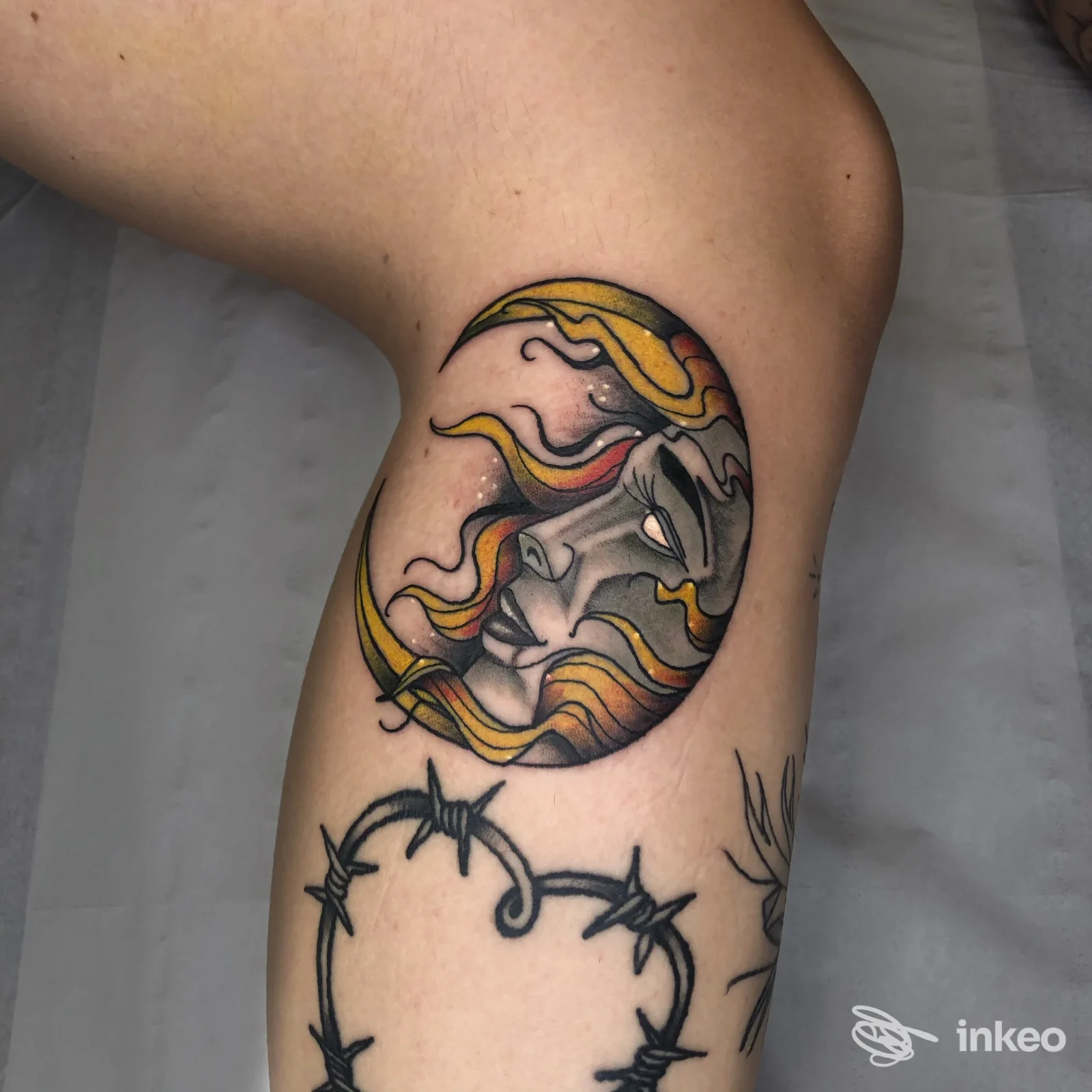 Tatuaggi su interno braccio: mezzaluna con volto stilizzato e onde gialle/rosse sopra un cuore di filo spinato. No Pain Tattoo Studio, Rossano Veneto.
