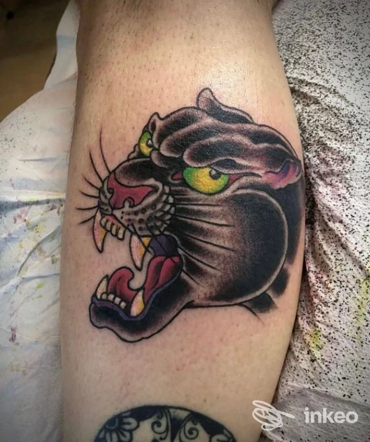 Tatuaggio a colori di una testa di pantera in stile tradizionale sul polpaccio, eseguito presso SYMBOLS - Professional Body Piercing & Walk-in Tattoo Shop, Verona.
