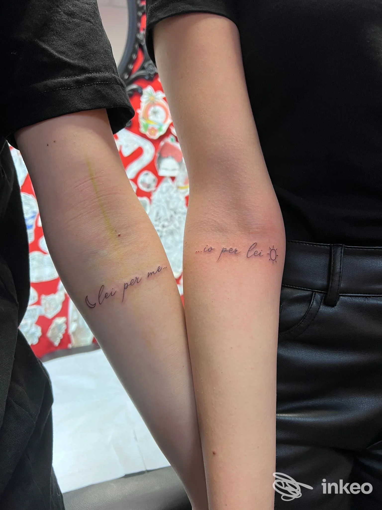 Due avambracci con tatuaggi in corsivo sulla pelle, non è visibile alcun volto.