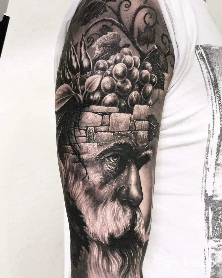 Grande tatuaggio realistico black & grey su braccio superiore con ritratto e grappolo d'uva, Speranza Tatuaggi, Vicenza.