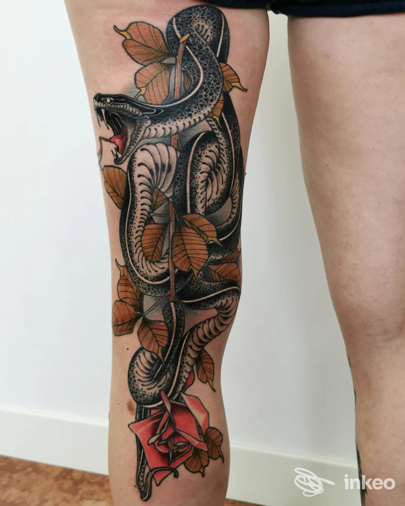 Tatuaggio di serpente con foglie e rosa su gamba, eseguito da Speranza Tatuaggi a Vicenza.