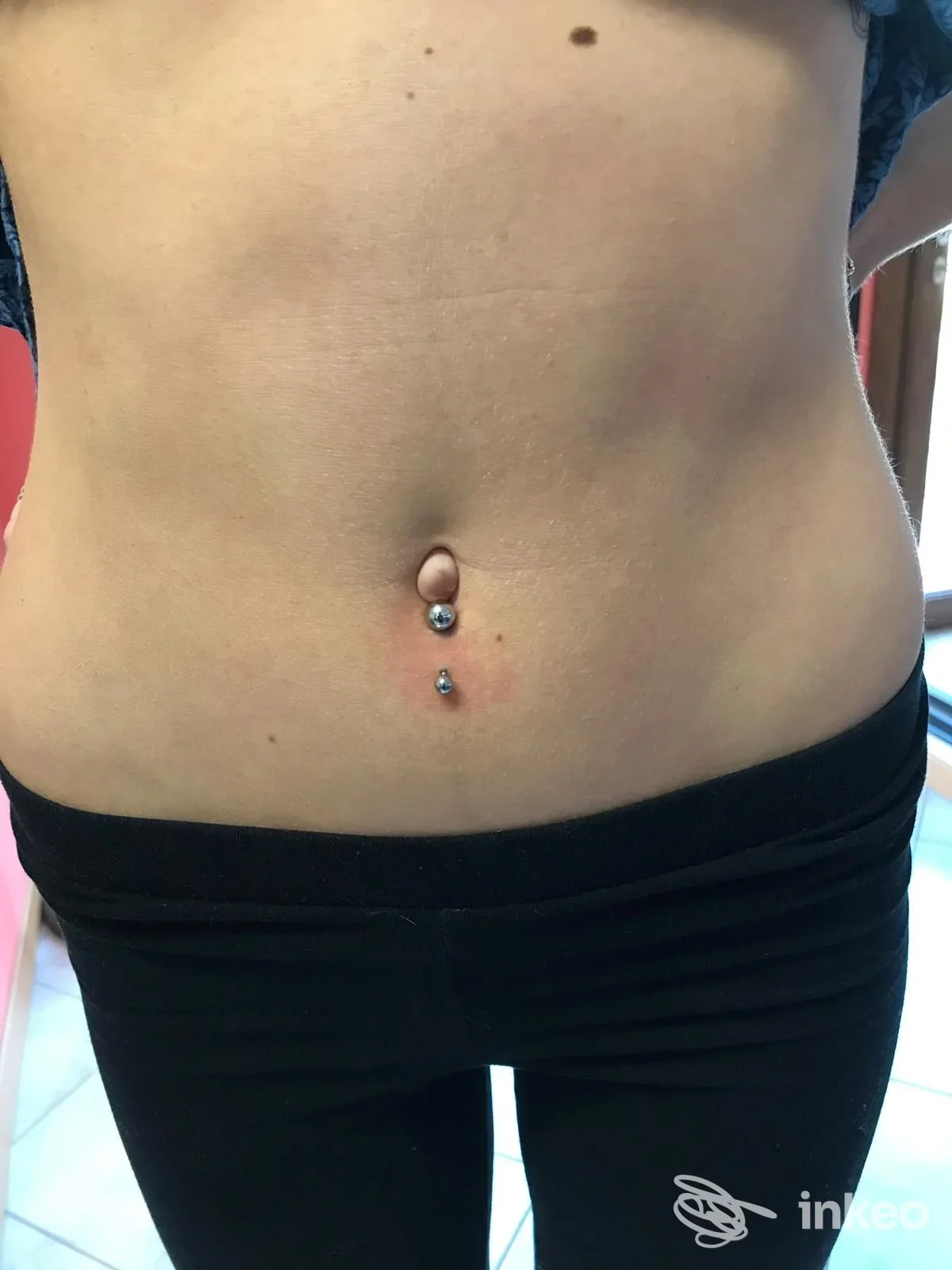 Piercing all'ombelico con gioiello verticale, fotografato sul tronco; immagine inviata da Studio Tatuaggi & Piercing Treviso, Musano.