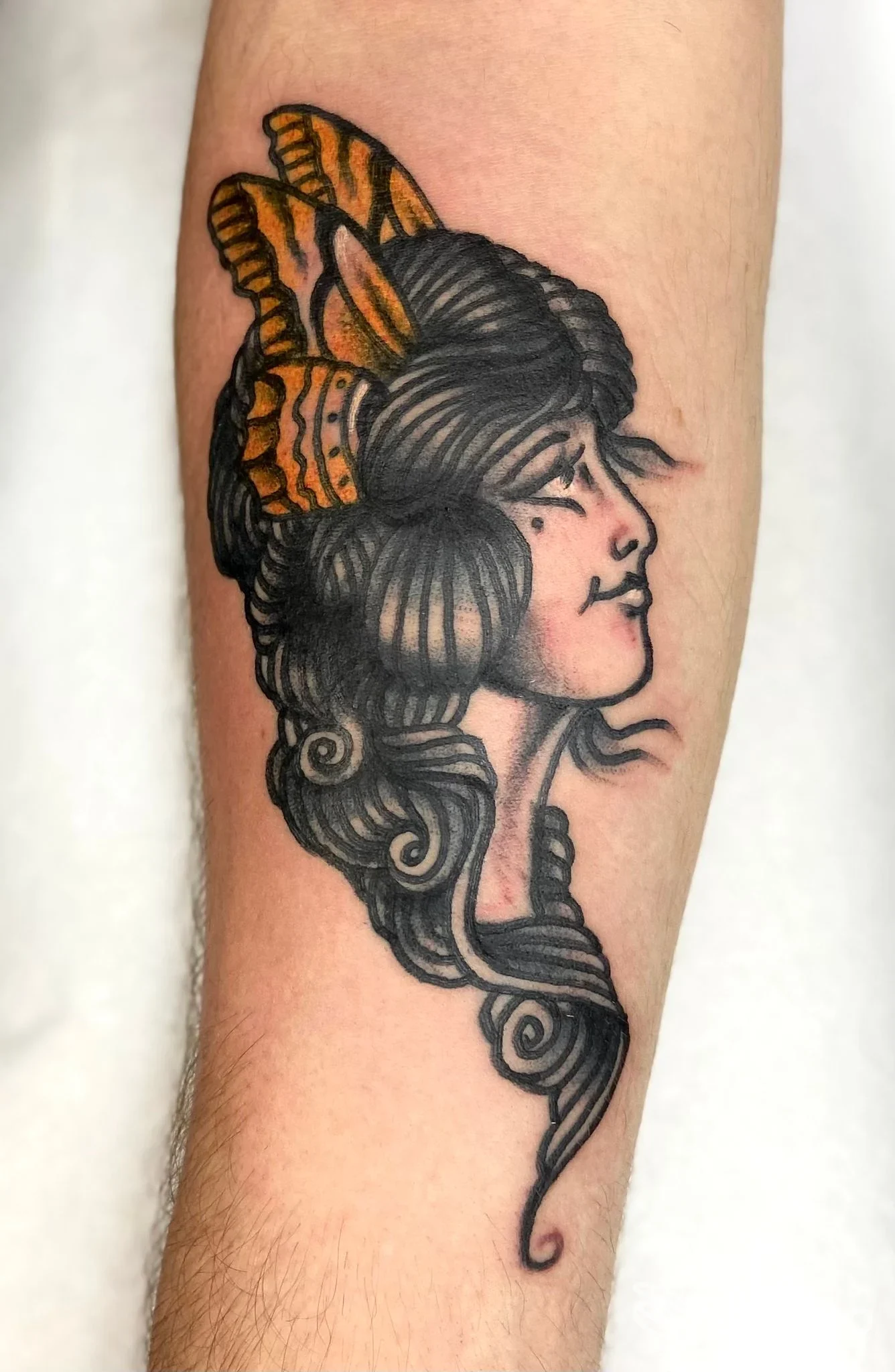 Tatuaggio su avambraccio raffigurante profilo femminile con decorazione arancione. Pain[t] of Mind - Montegalda.