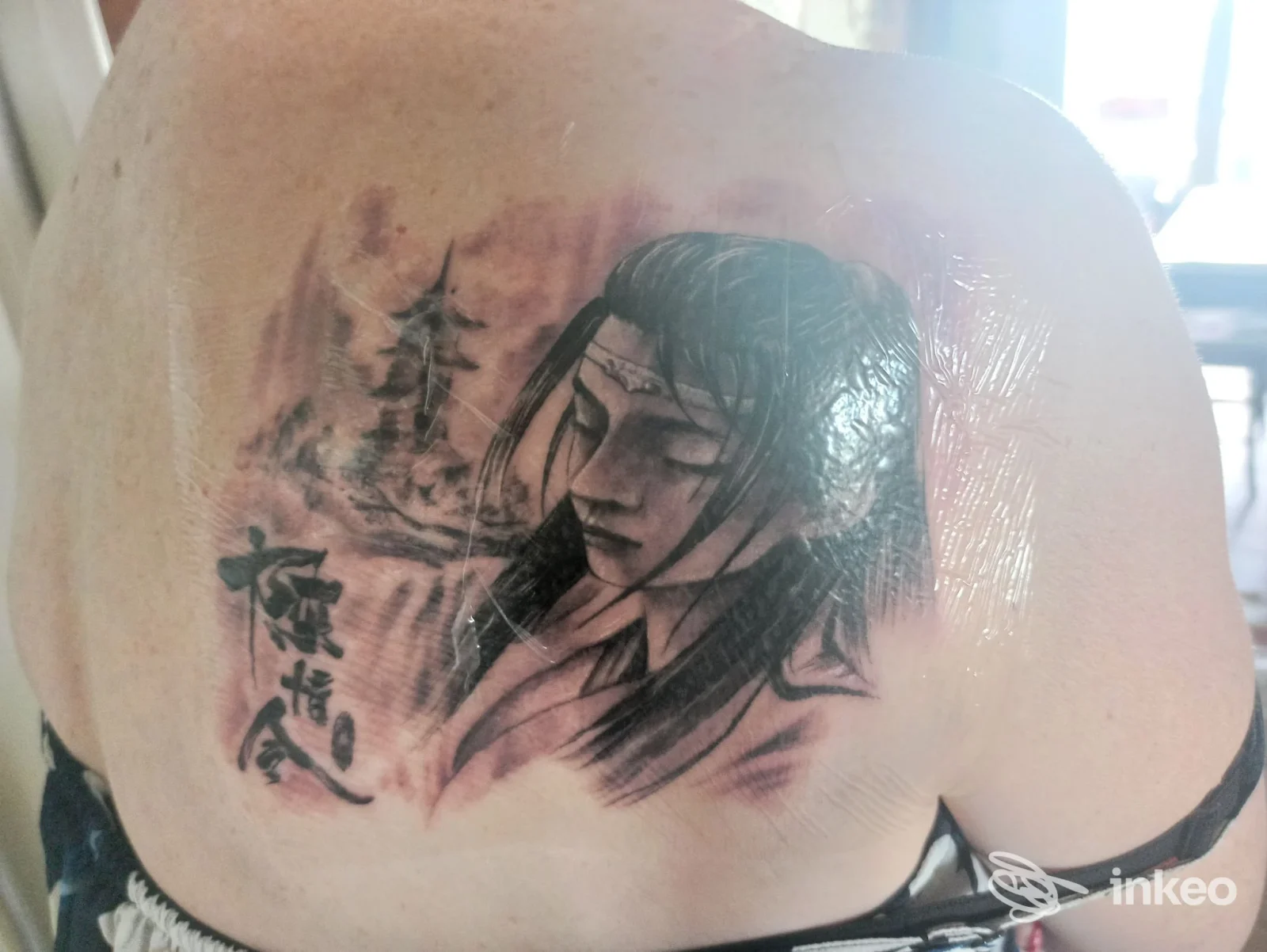 Tatuaggio in bianco e nero sulla spalla/schiena con ritratto stilizzato e caratteri, foto fornita da Tattoo Studio Santi E Peccatori, Padova.