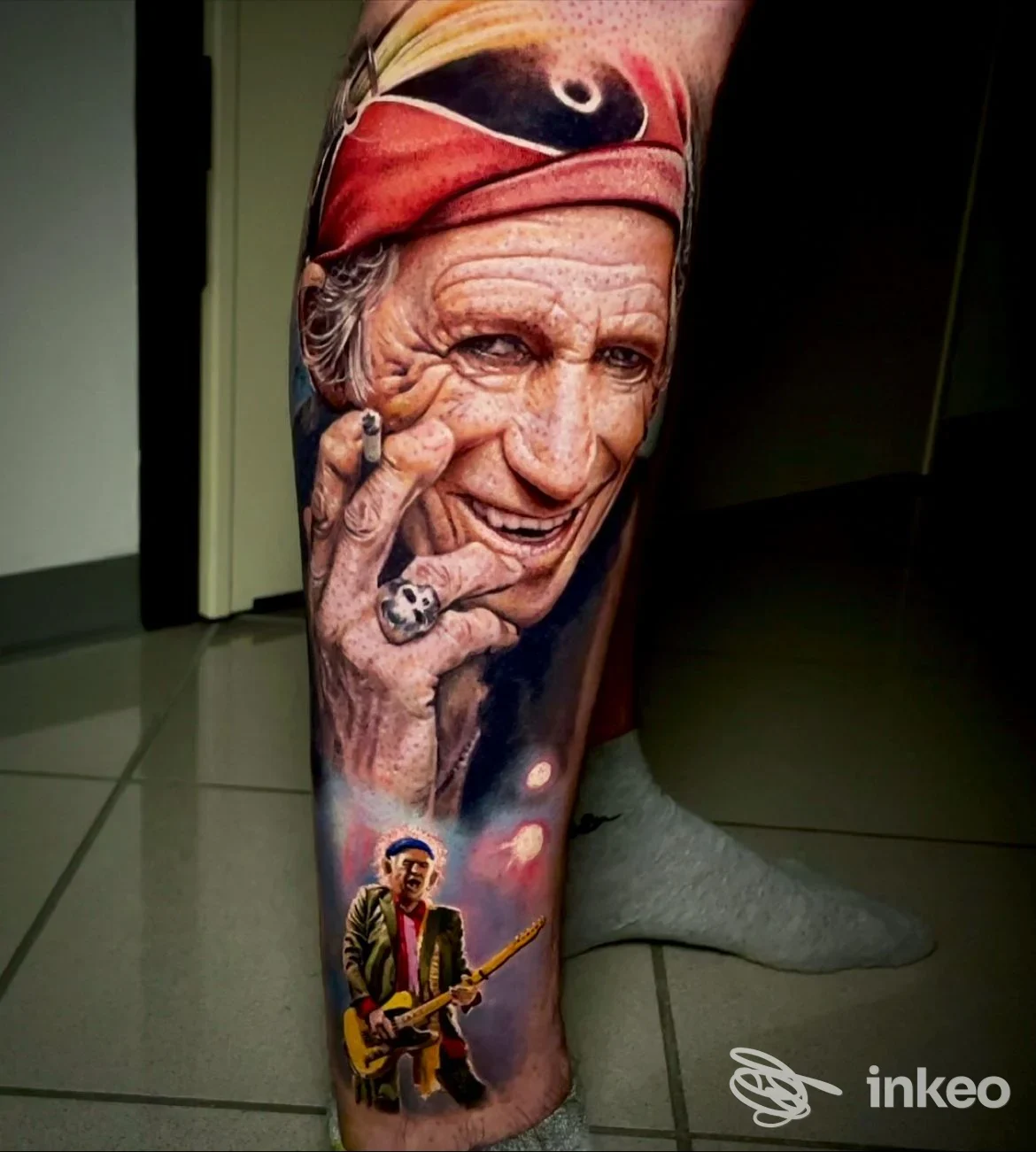 Grande tatuaggio realistico su polpaccio con ritratto che fuma e piccolo chitarrista, foto inviata dallo studio TattooLAB di Oderzo