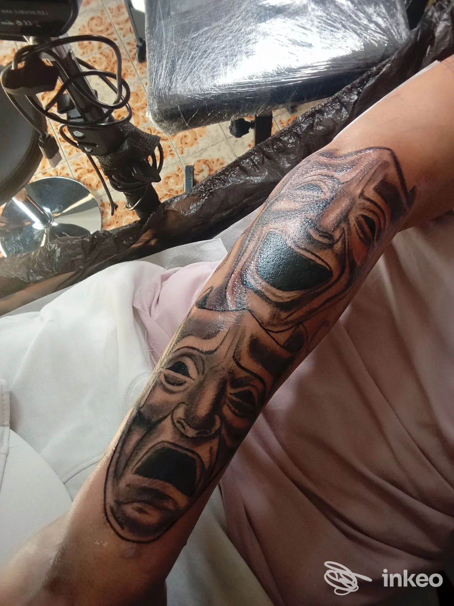 Tatuaggio in bianco e nero con maschere teatrali lungo l'avambraccio, foto inviata da Young Blood Tattoo Studio, Cassola.