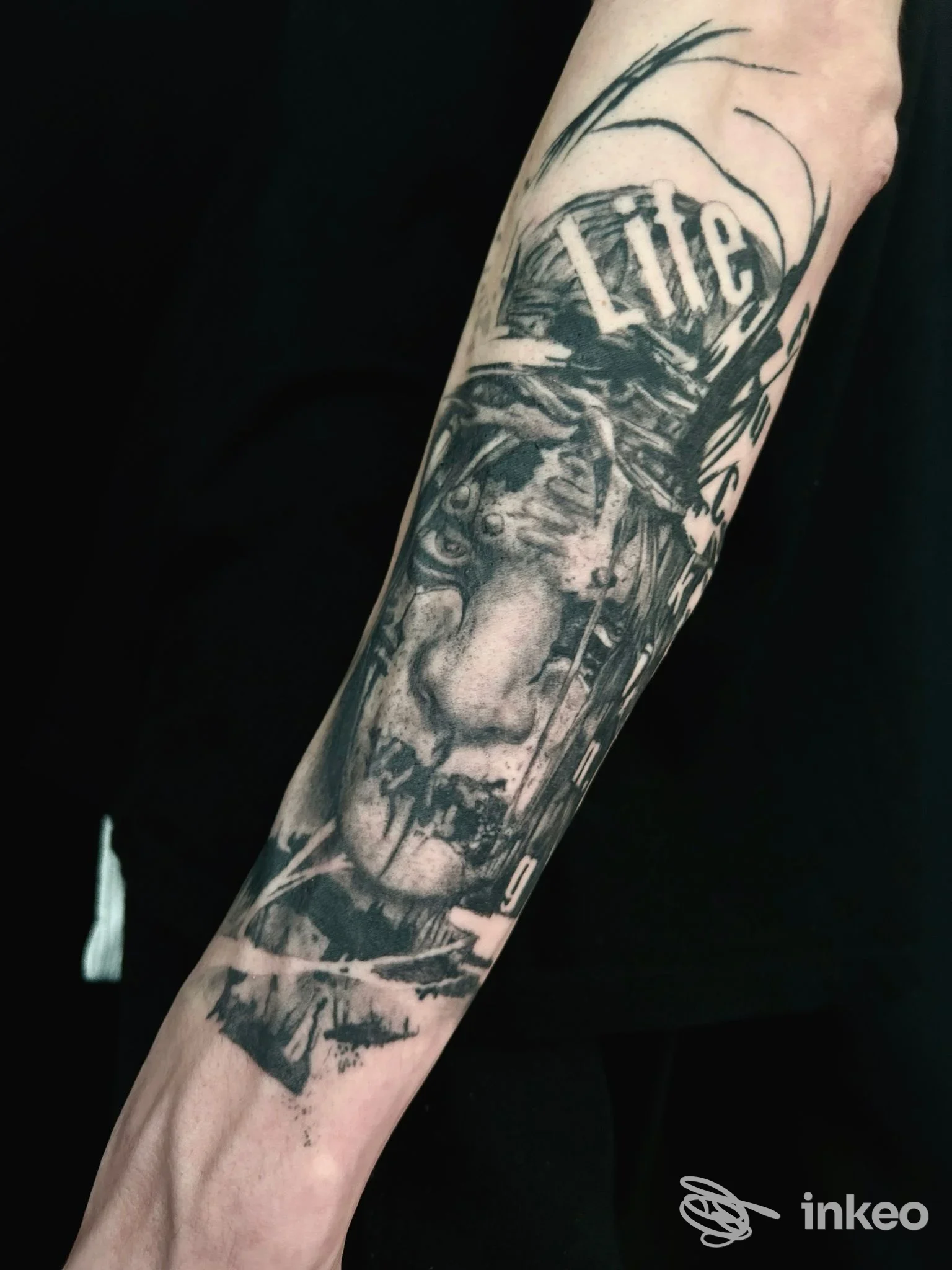 Tatuaggio realistico in bianco e nero su avambraccio con volto stilizzato e lettering, lavoro di vanleleink tattoo a Oriago.
