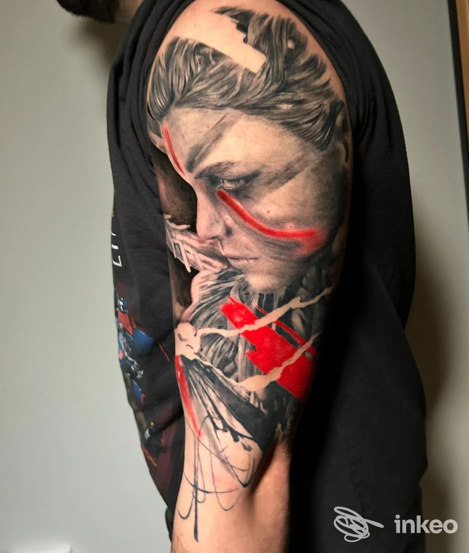Ampio tatuaggio realistico su spalla e braccio con volto e accenti rossi, vanleleink tattoo, Oriago.