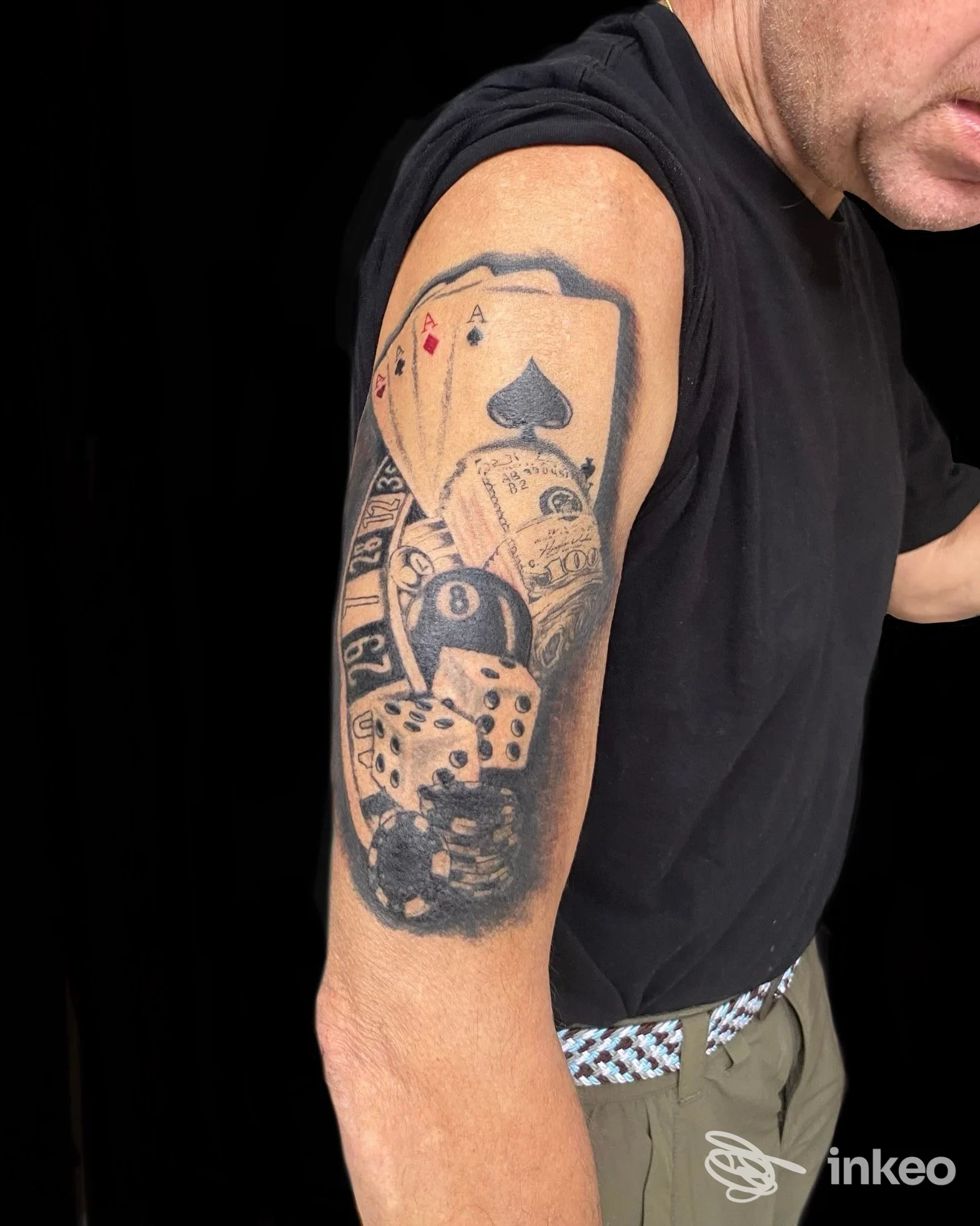 Tatuaggio a tema gioco d'azzardo sul bicipite, foto fornita da The Chico's tattoo, Rosà.
