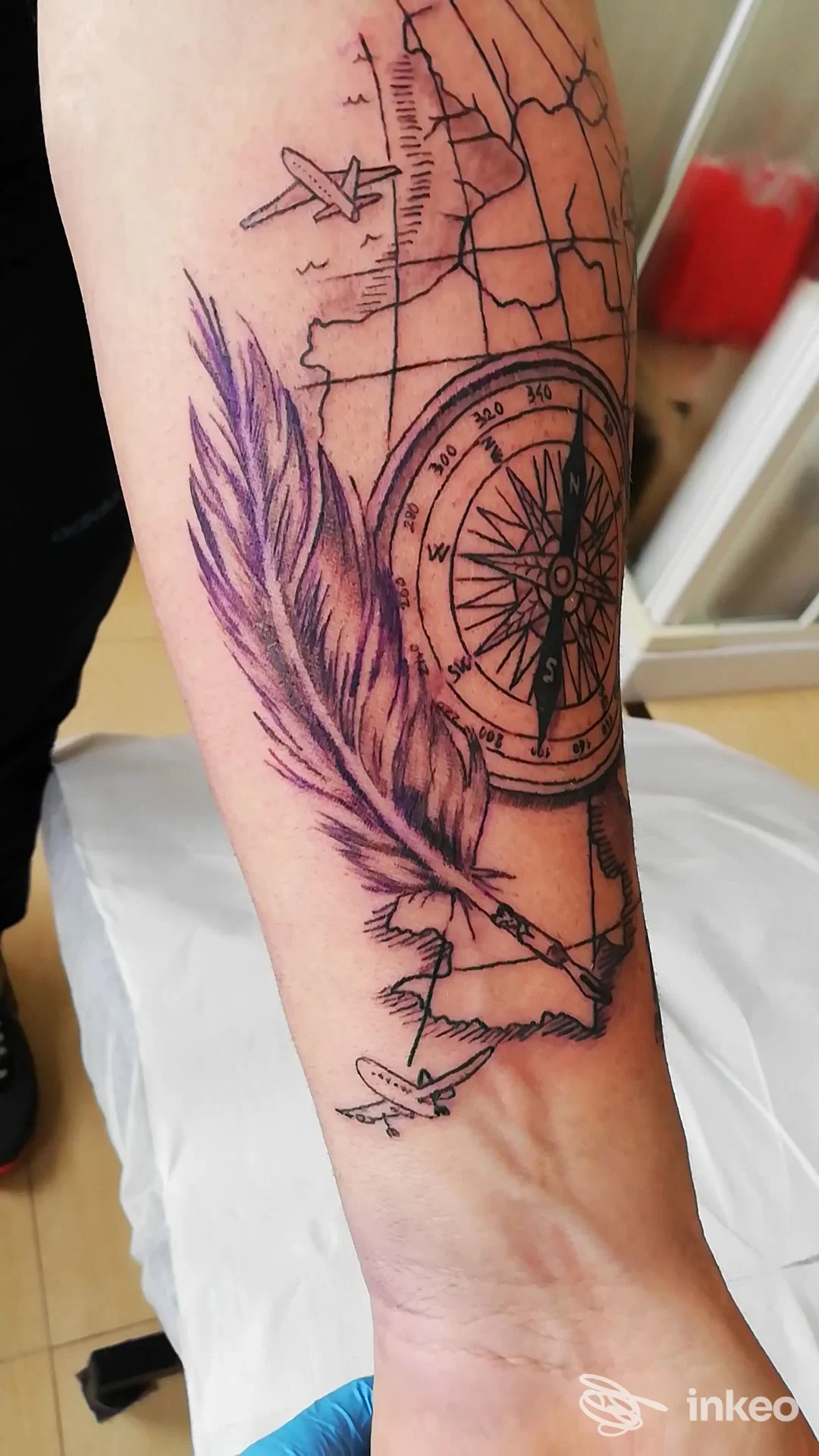 Tatuaggio su avambraccio con bussola, piuma e mappa realizzato da Zerbi Tattoo a Mogliano Veneto.