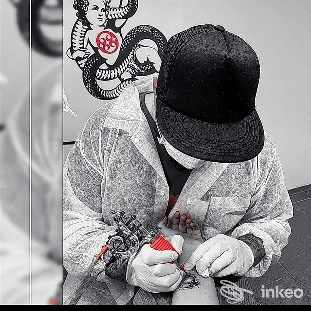 Tatuatore di ATMA TATTOO a Melfi al lavoro sull'avambraccio di un cliente, primo piano sull'applicazione del tattoo.