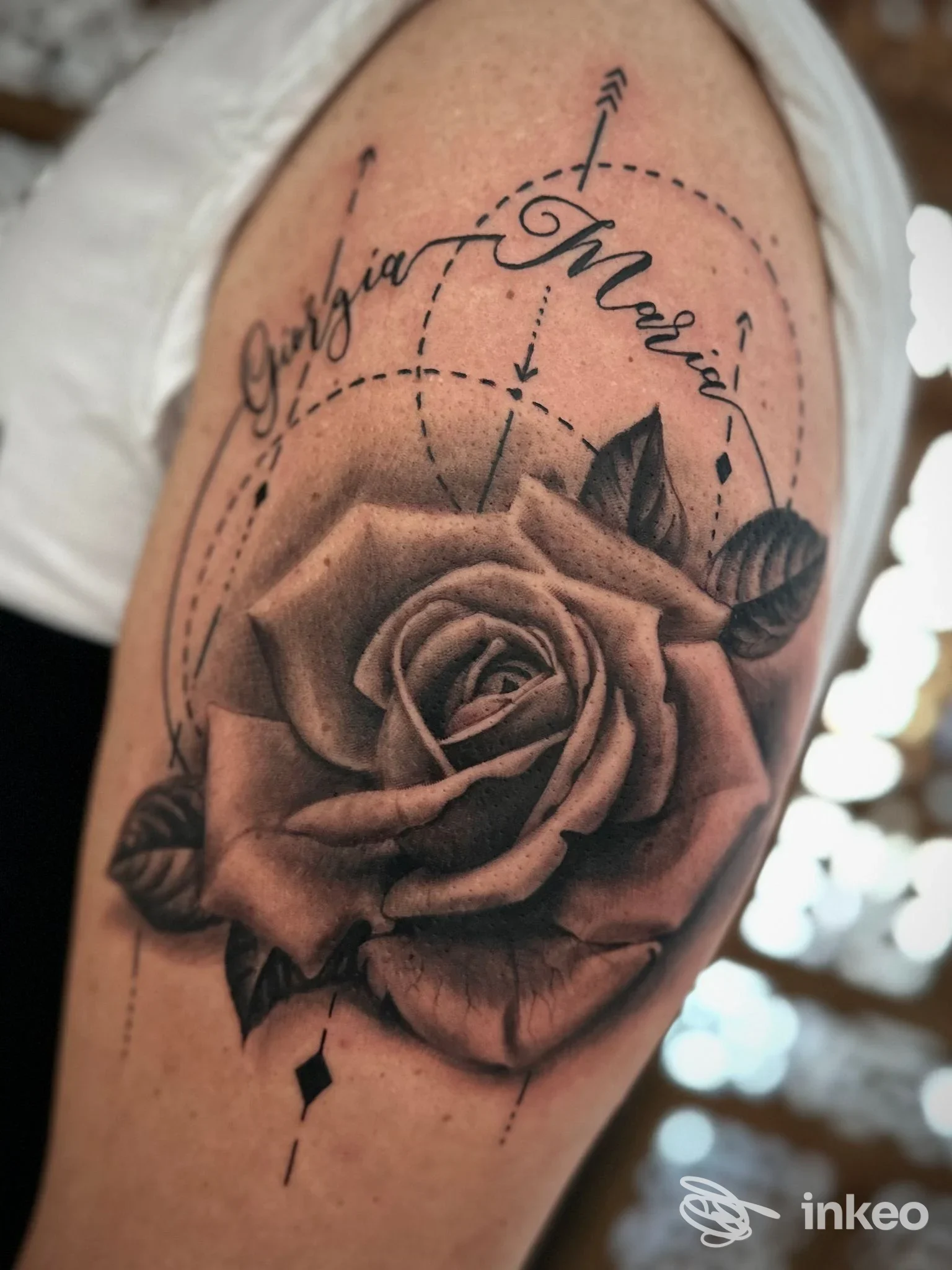 Tatuaggio realistico black & grey: grande rosa con foglie e scritta corsiva sul braccio superiore. Atavic Tattoo, Rionero in Vulture.
