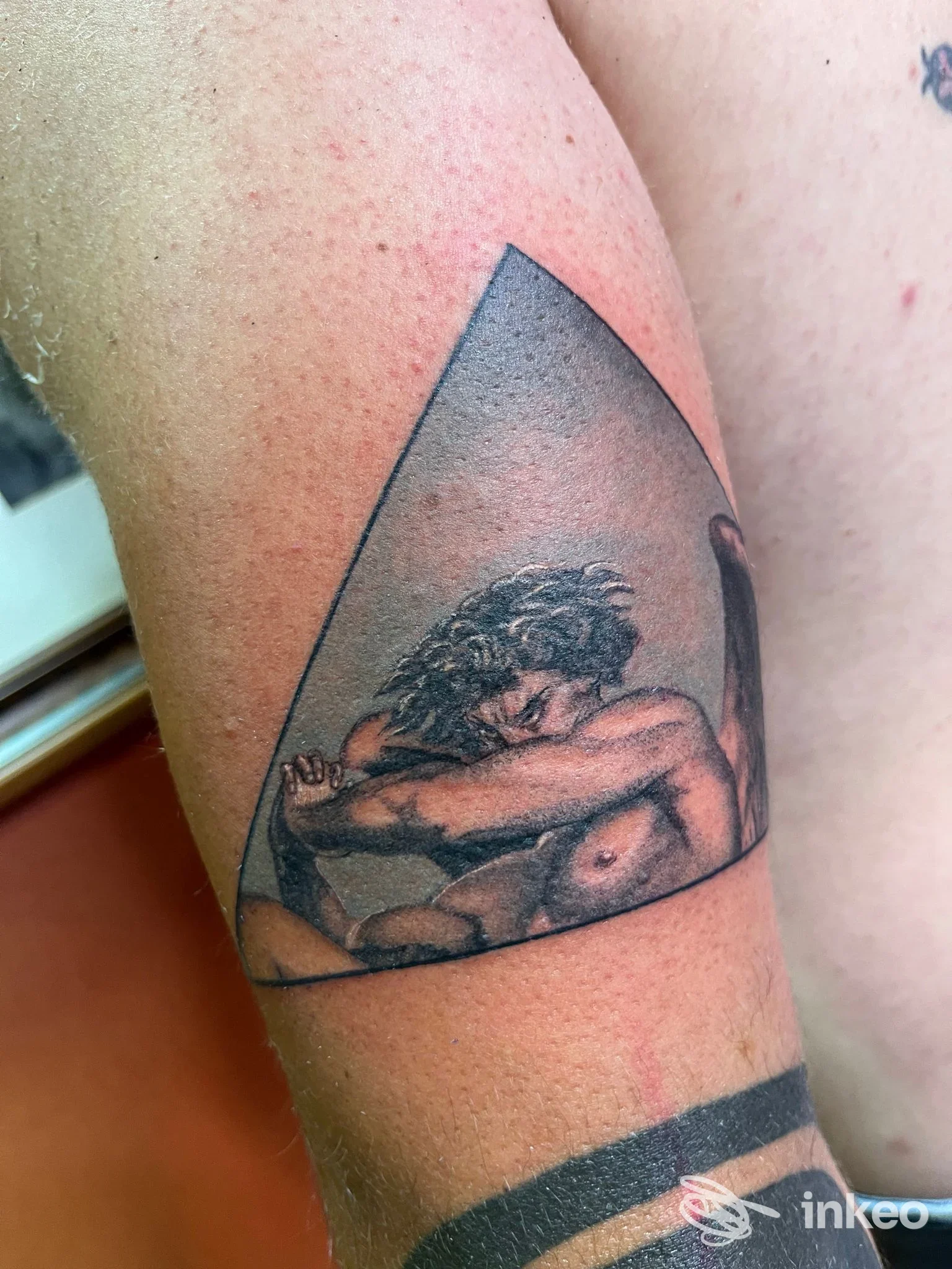 Tatuaggio black & grey di figura umana rannicchiata in un triangolo sull'avambraccio, foto fornita da Deep South Art TATTOO studio, Bernalda.