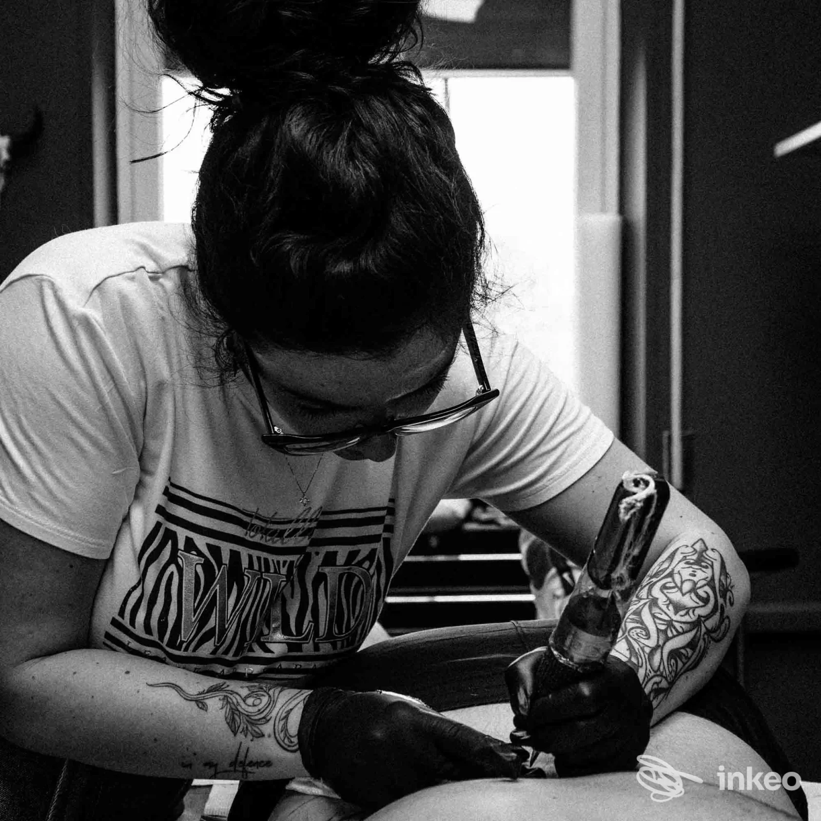 Artista di Minerva Studio Tattoo a Matera al lavoro su una gamba di cliente: primo piano sulla macchinetta e sul tatuaggio in fase di esecuzione.