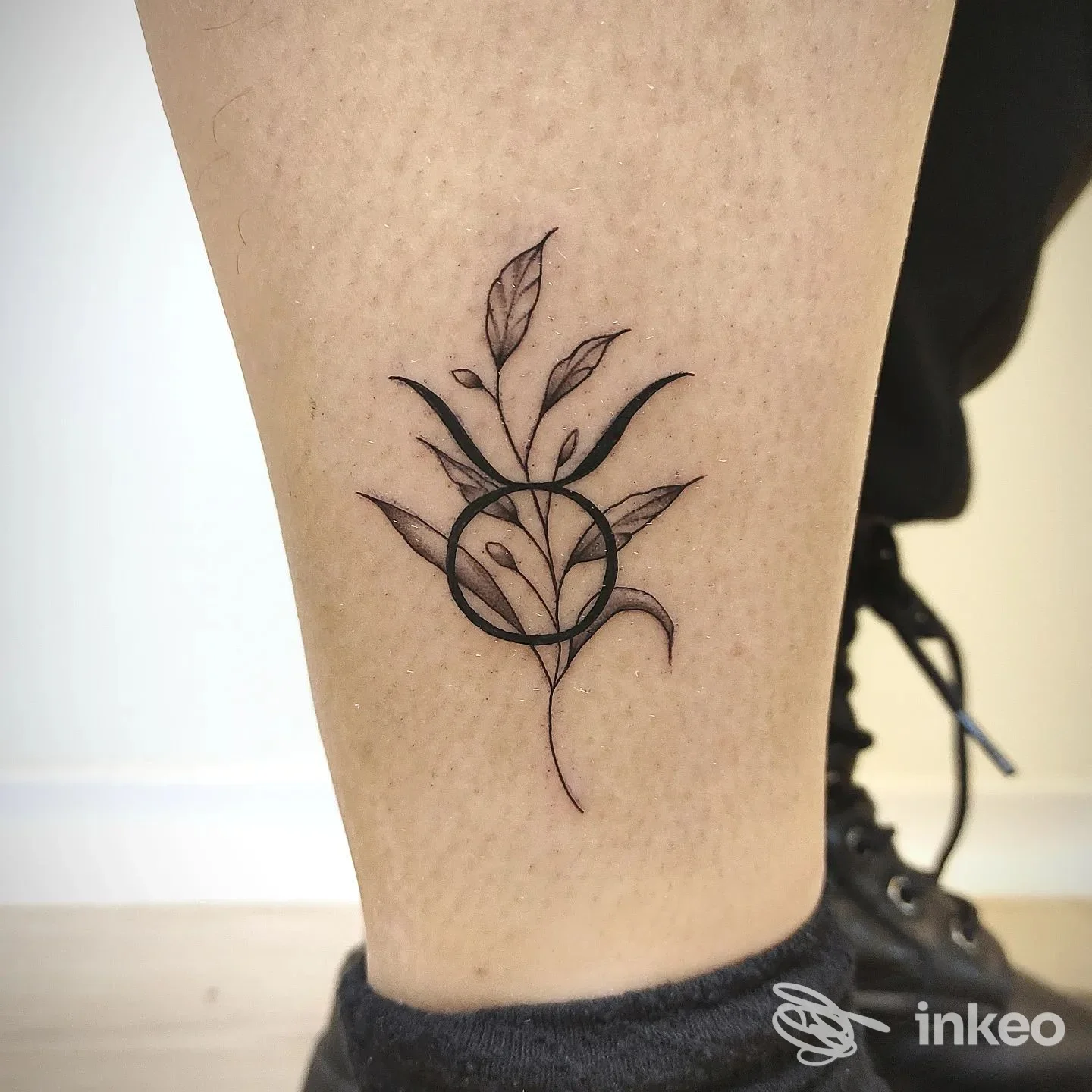Tatuaggio botanico nero a linee sottili sul polpaccio basso, eseguito da NeverendINK Tattoo a Matera.