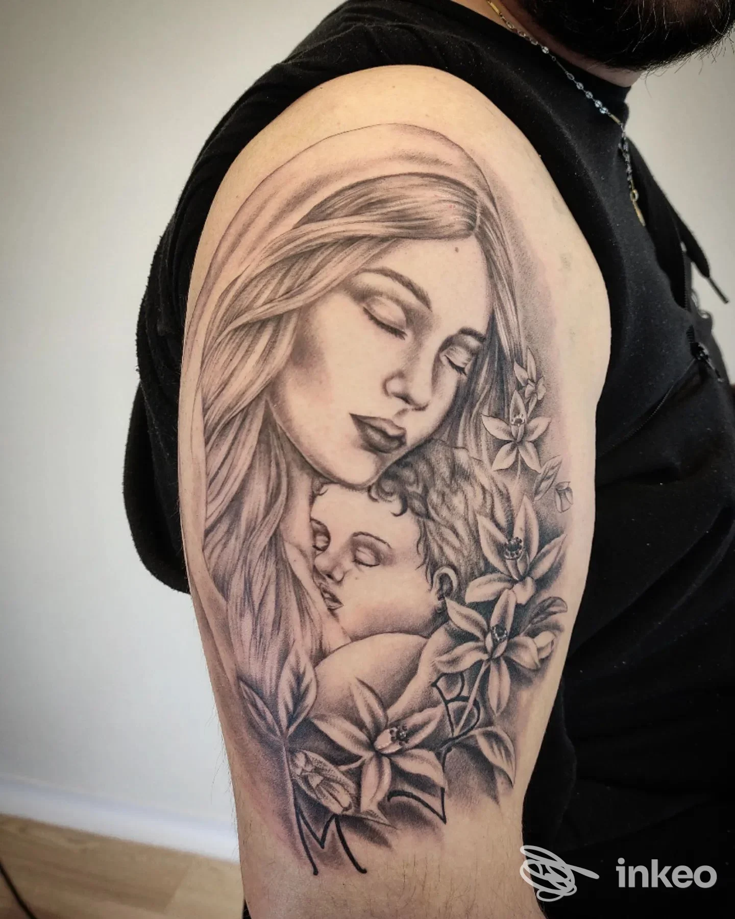 Tatuaggio realista in bianco e nero di Madonna con bambino sull'omero, foto fornita da NeverendINK Tattoo a Matera.