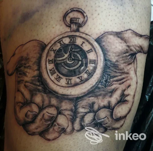 Tatuaggio black & grey su coscia che mostra due mani che reggono un orologio da tasca, Off Ink Tattoo, Tricarico.