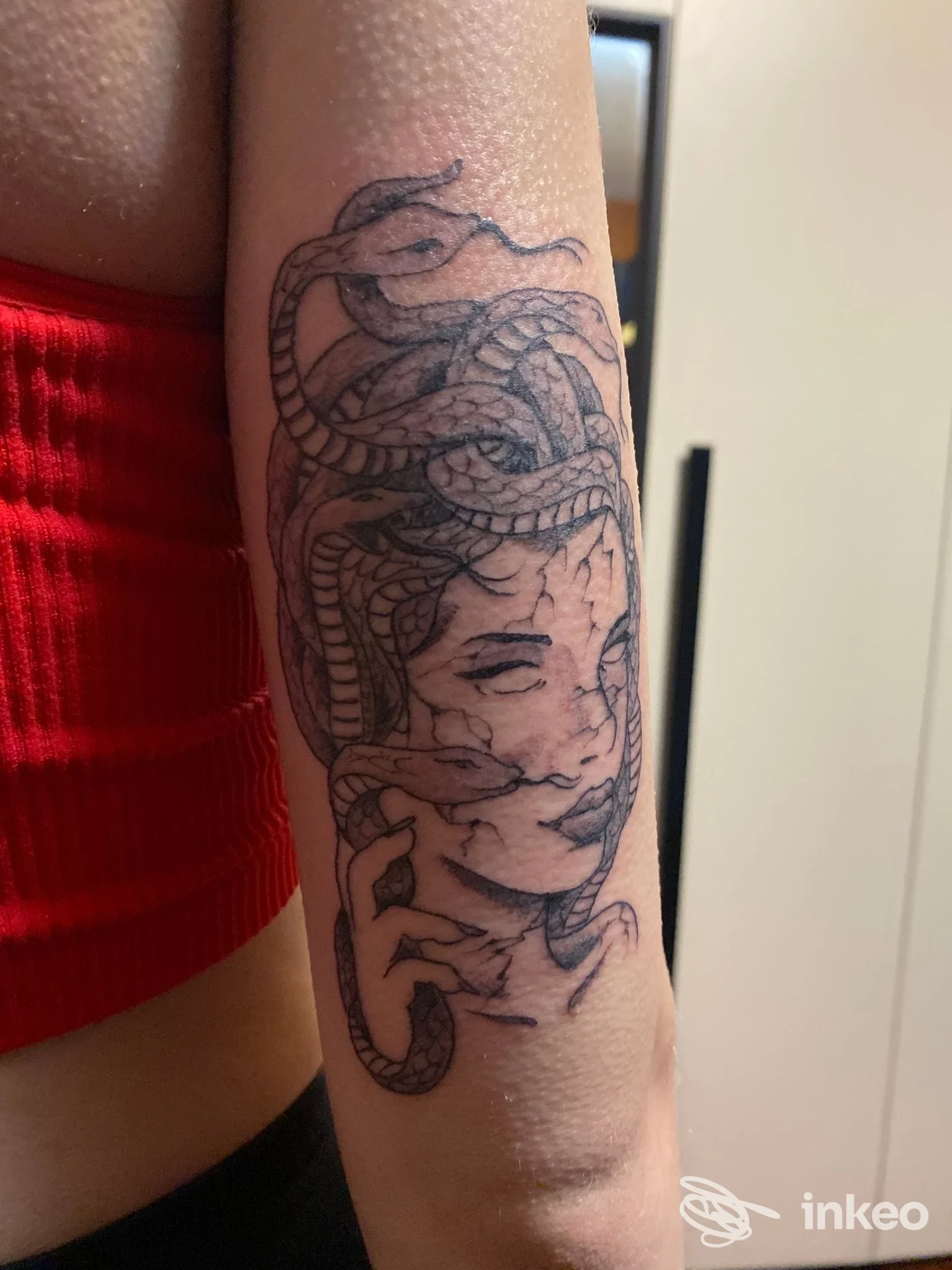 Tattoo sul avambraccio sinistro raffigurante una testa femminile avvolta da serpenti intrecciati, disegno in stile linework.