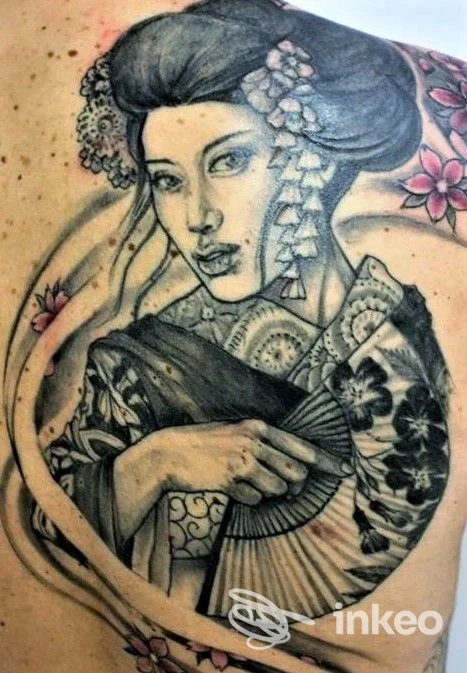 Tatuaggio realistico di una geisha in bianco e nero con fiori rosa, realizzato da Peccati di Pelle Tattoo a Potenza.