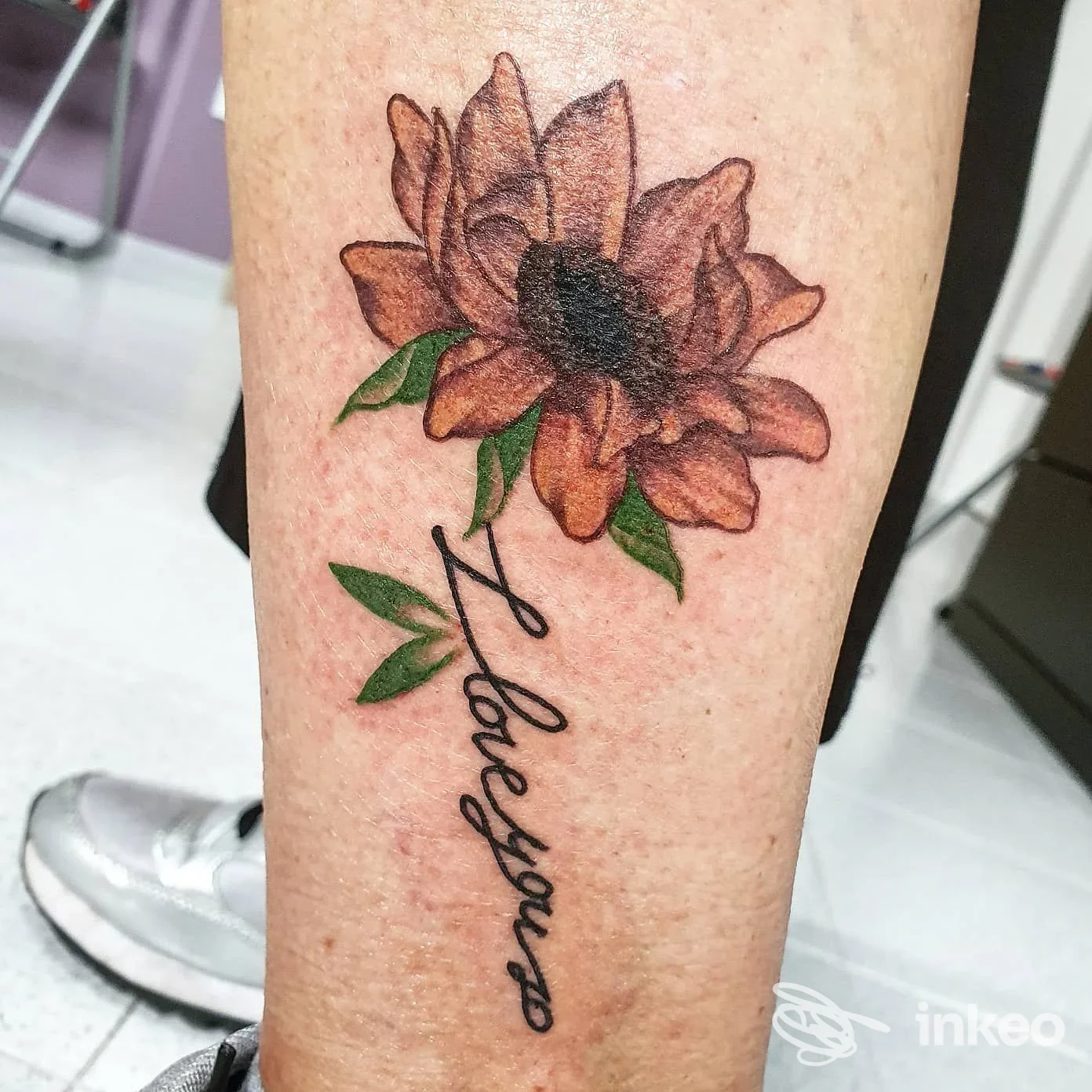 Tatuaggio floreale colorato con scritta corsiva sul polpaccio/avambraccio, scattato presso Poison Tattoo Studio a Potenza.