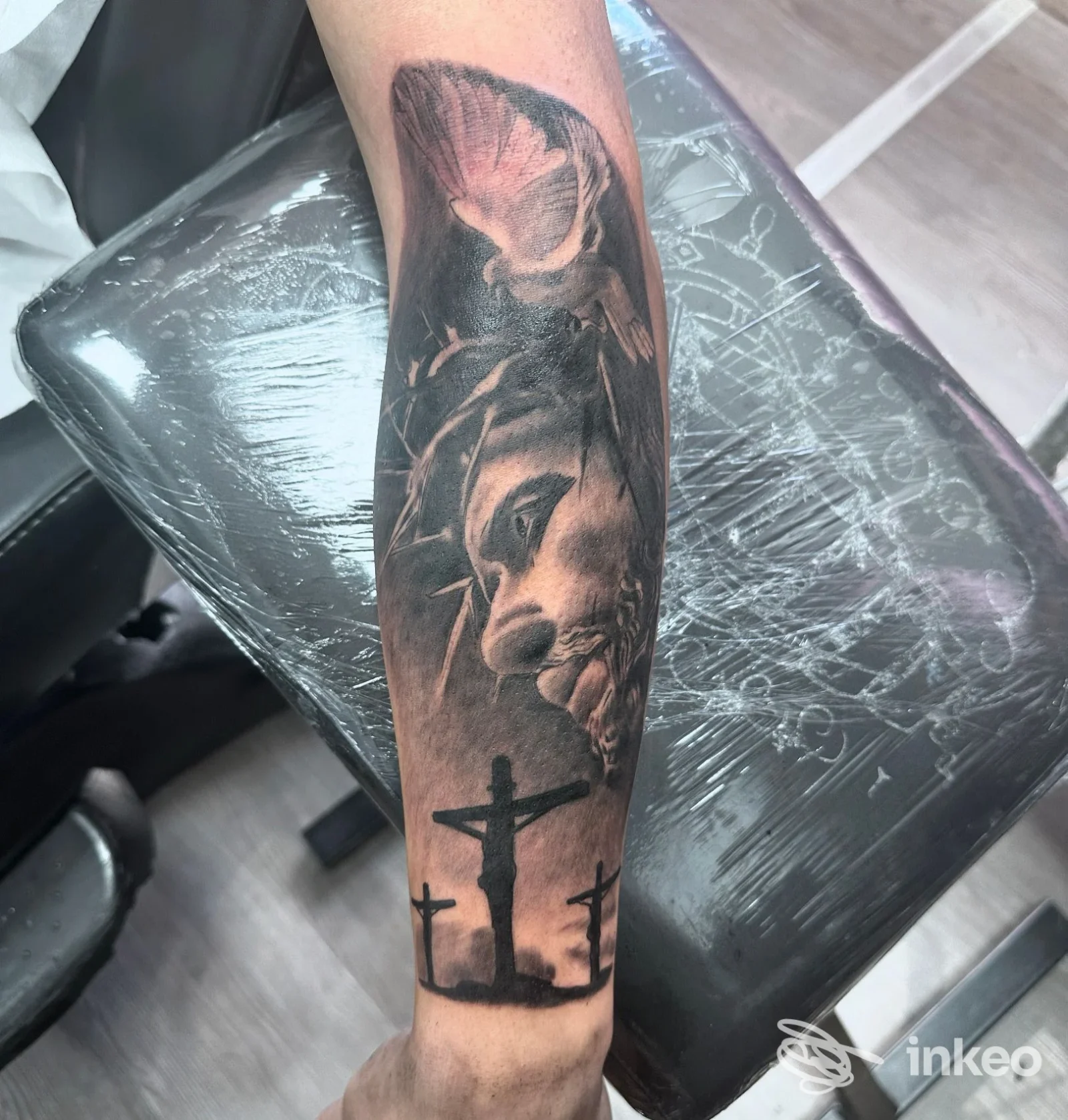 Avambraccio tatuato con volto realistico e scena di tre crocifissi, immagine fornita da THE BLACKCHERRY TATTOO STUDIO, Potenza.