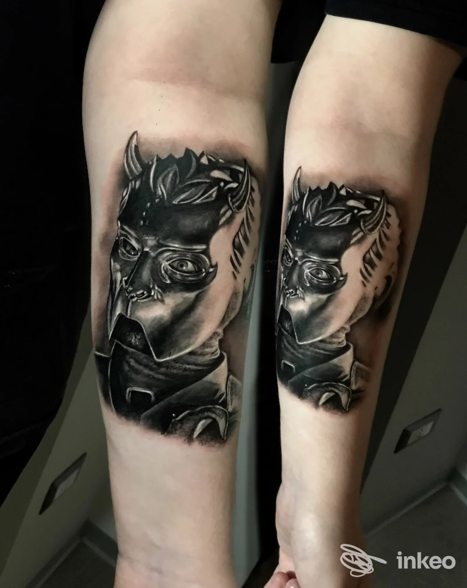 Tatuaggio realistico in bianco e nero raffigurante un volto mascherato sull'avambraccio, immagine da Tattoo Art Studio, Montescaglioso.