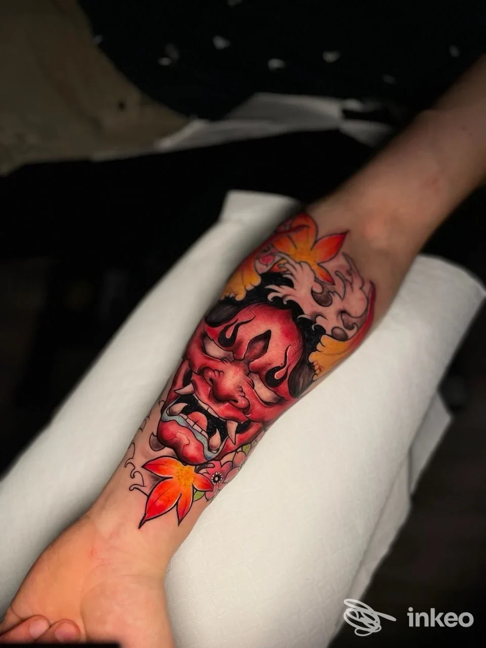 Avambraccio tatuato con una maschera rossa e dettagli fiammeggianti arancioni e gialli; lavoro realizzato da Sorry mom tattoo shop, Matera.