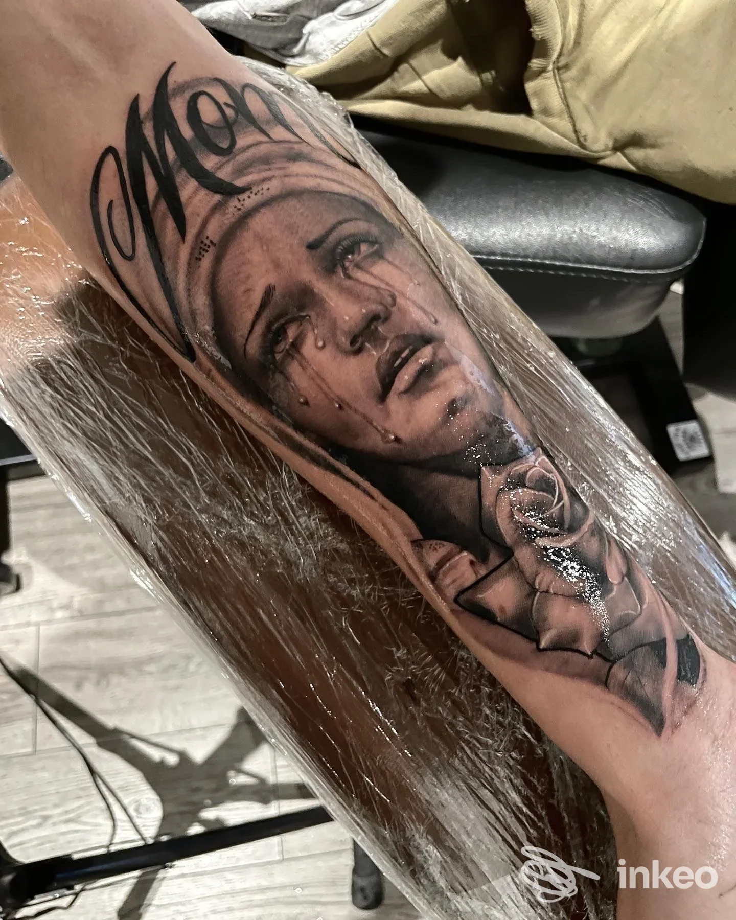 Primo piano di tatuaggio realistico su avambraccio con volto femminile in lacrime e rosa, realizzato da Sorry mom tattoo shop a Matera.