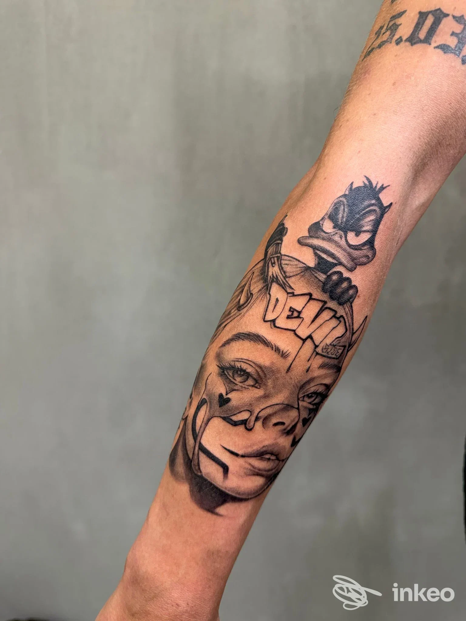 Tatuaggio black & grey su avambraccio con volto femminile e personaggio in stile cartoon, foto fornita da kalashnikov art shop tattoo a Genova.