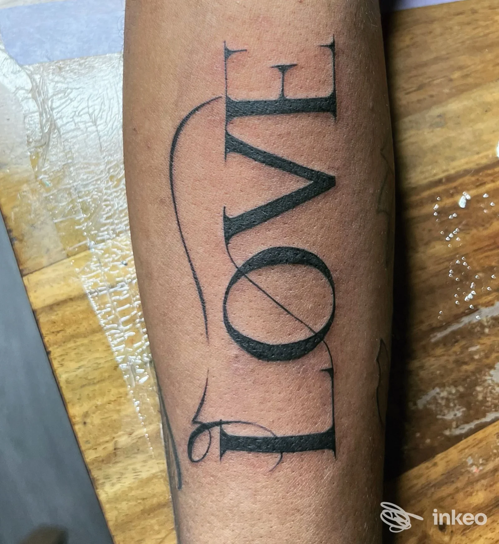 Tatuaggio lettering "LOVE" in nero sull'avambraccio, foto fornita da kalashnikov art shop tattoo, Genova.