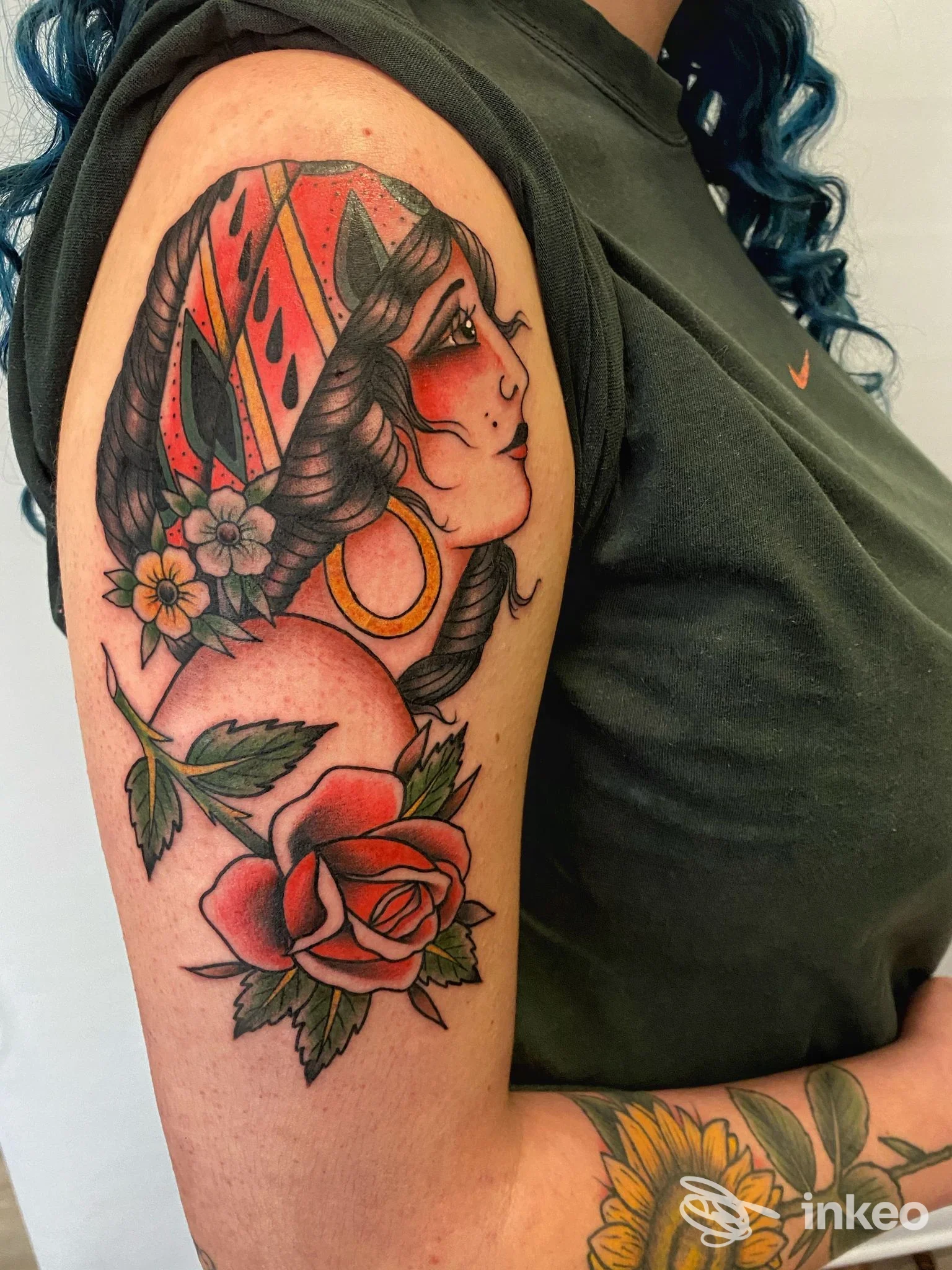 Tatuaggio colorato tradizionale di una testa femminile e una rosa sull'alto braccio, realizzato da Sacred Bones Tattoo Bolzano, Bolzano.